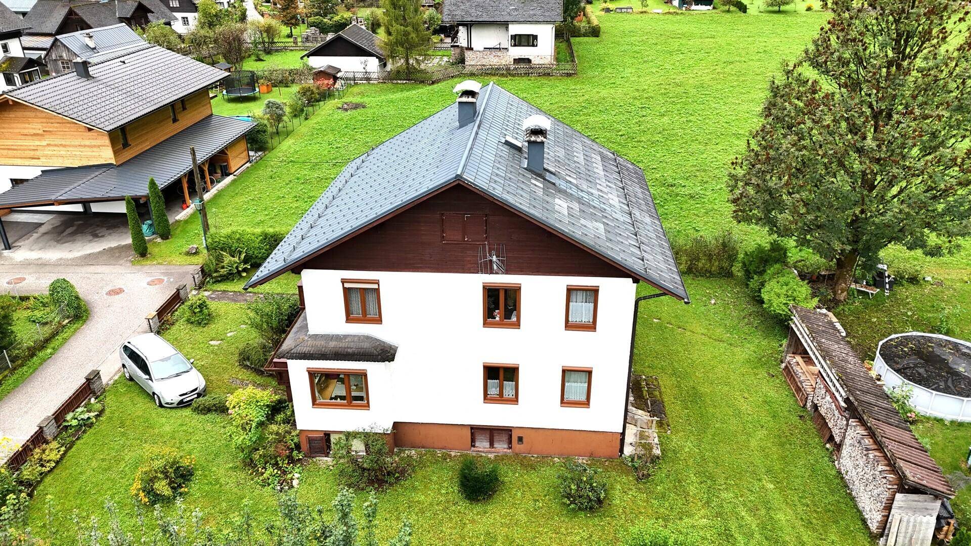 Dachansicht des Einfamilienhauses mit Garten und angrenzendem Carport des Nachbarhauses.