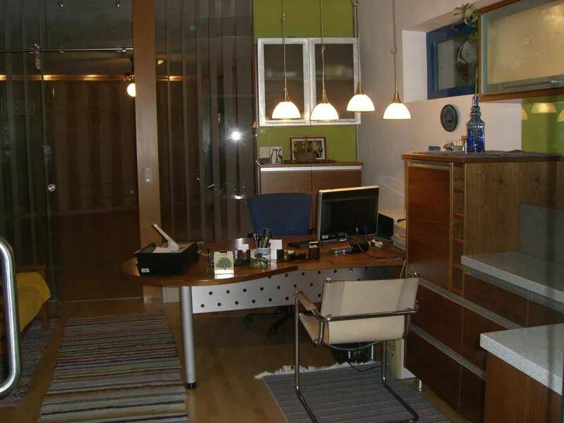 Modernes Büro mit Schreibtisch, Computer und grünen Wänden.