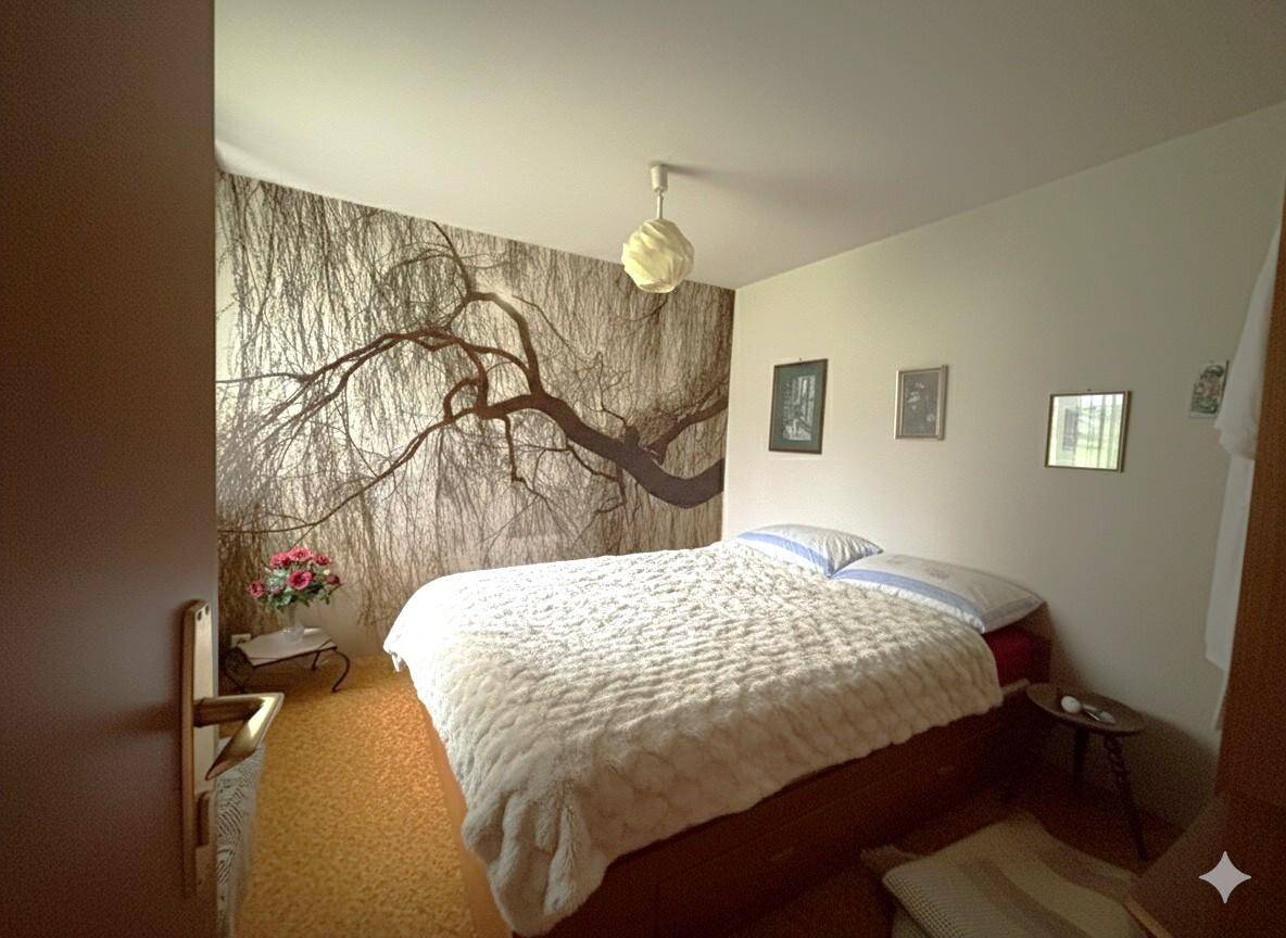 Schlafzimmer mit auffälliger Baum-Tapete, Doppelbett und Linoleumboden.