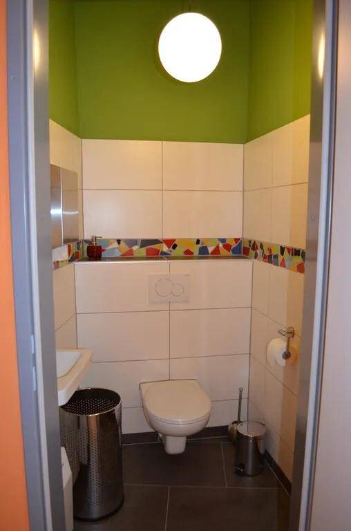 Moderne Gästetoilette mit farbenfrohem Mosaikband und Wand-WC.
