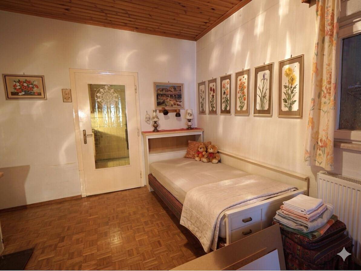 Schlafzimmer mit Einzelbett, Parkettboden und floralen Bildern an der Wand.