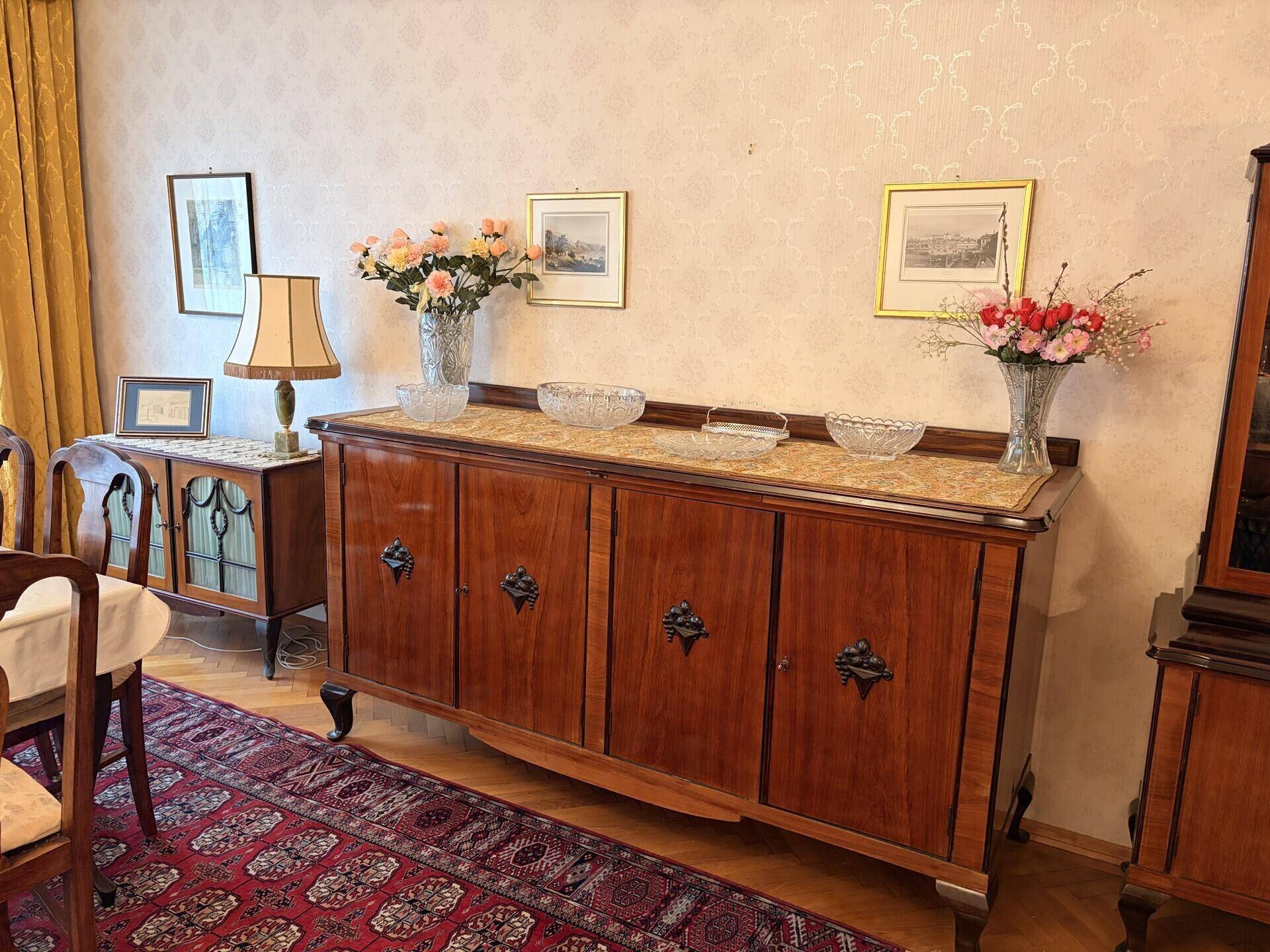 Detailansicht eines traditionellen Sideboards mit Marmorplatte und Blumenarrangements.