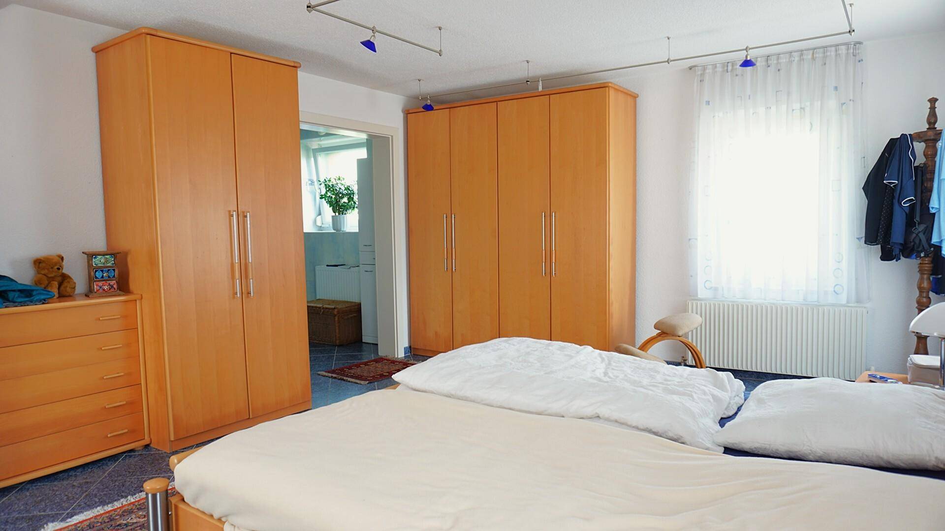 Schlafzimmer mit großen Holzschränken, Doppelbett und Zugang zum Badezimmer.