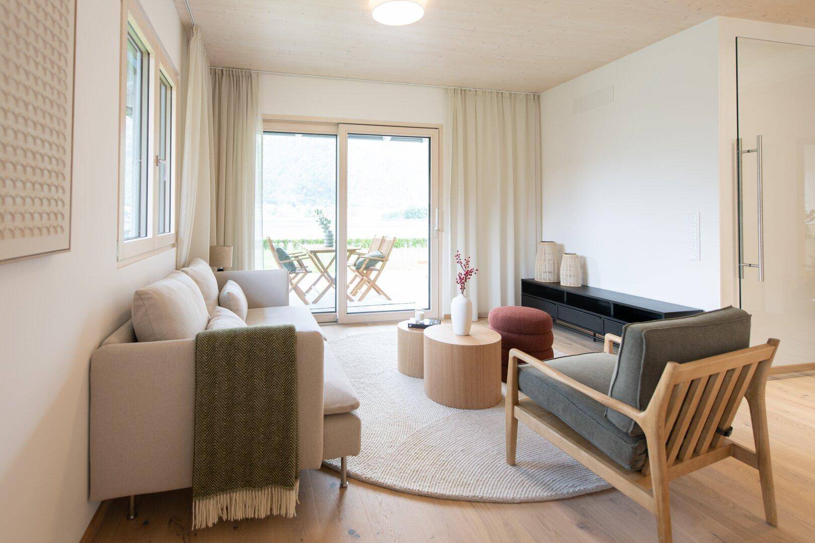 Gemütliches Wohnzimmer mit Holzboden, bequemen Möbeln und Terrassenzugang.