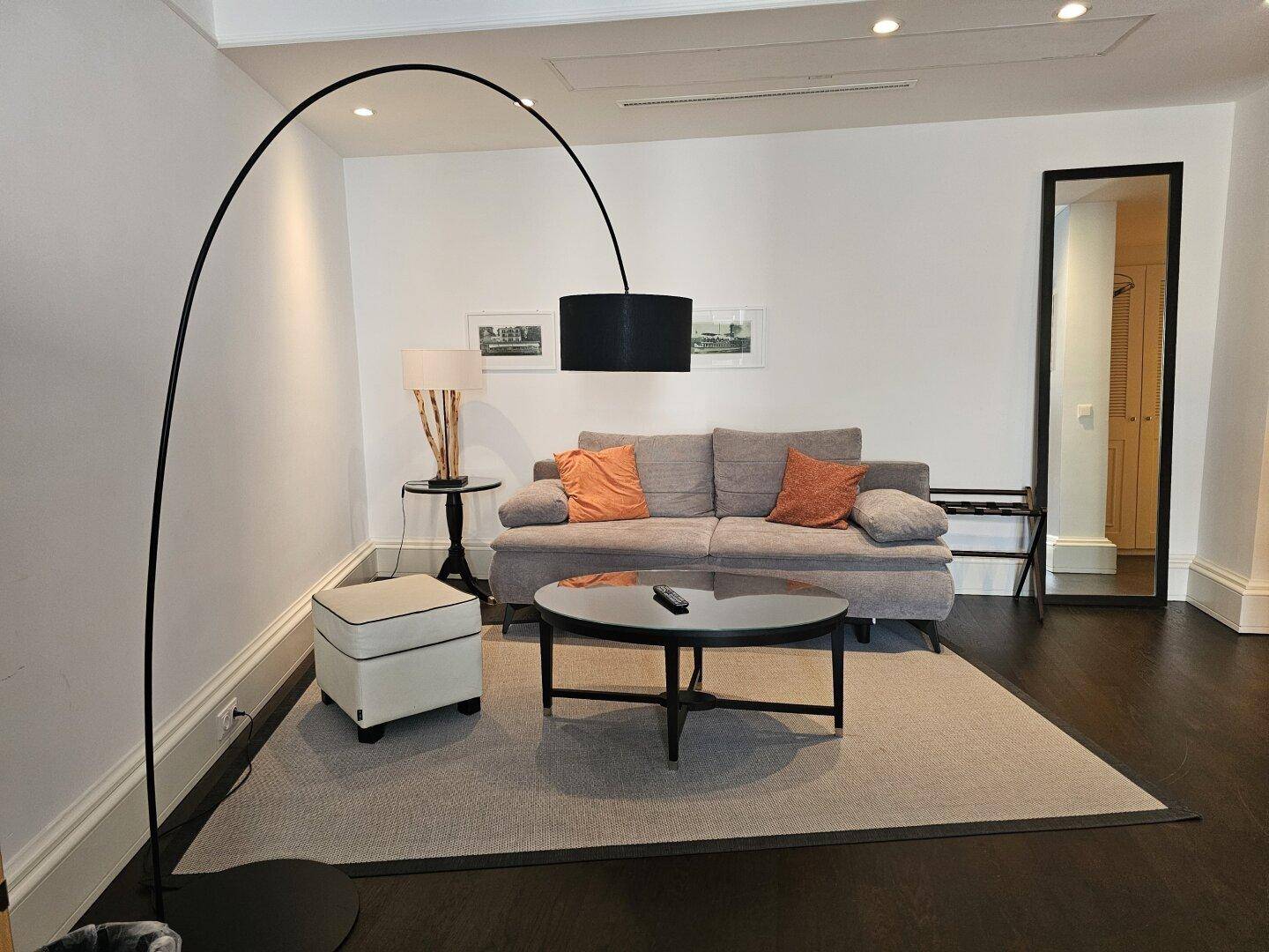 Gemütliches Wohnzimmer mit modernem Sofa, Couchtisch und eleganter Bogenlampe.