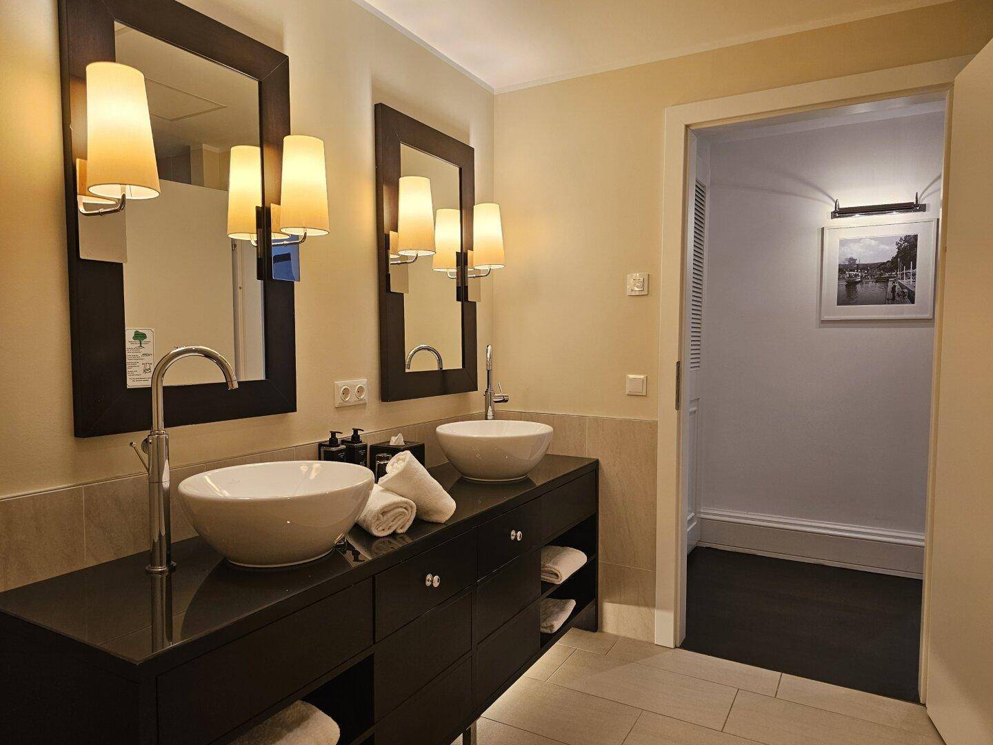 Elegantes Badezimmer mit Doppelwaschbecken, großen Spiegeln und indirekter Beleuchtung.