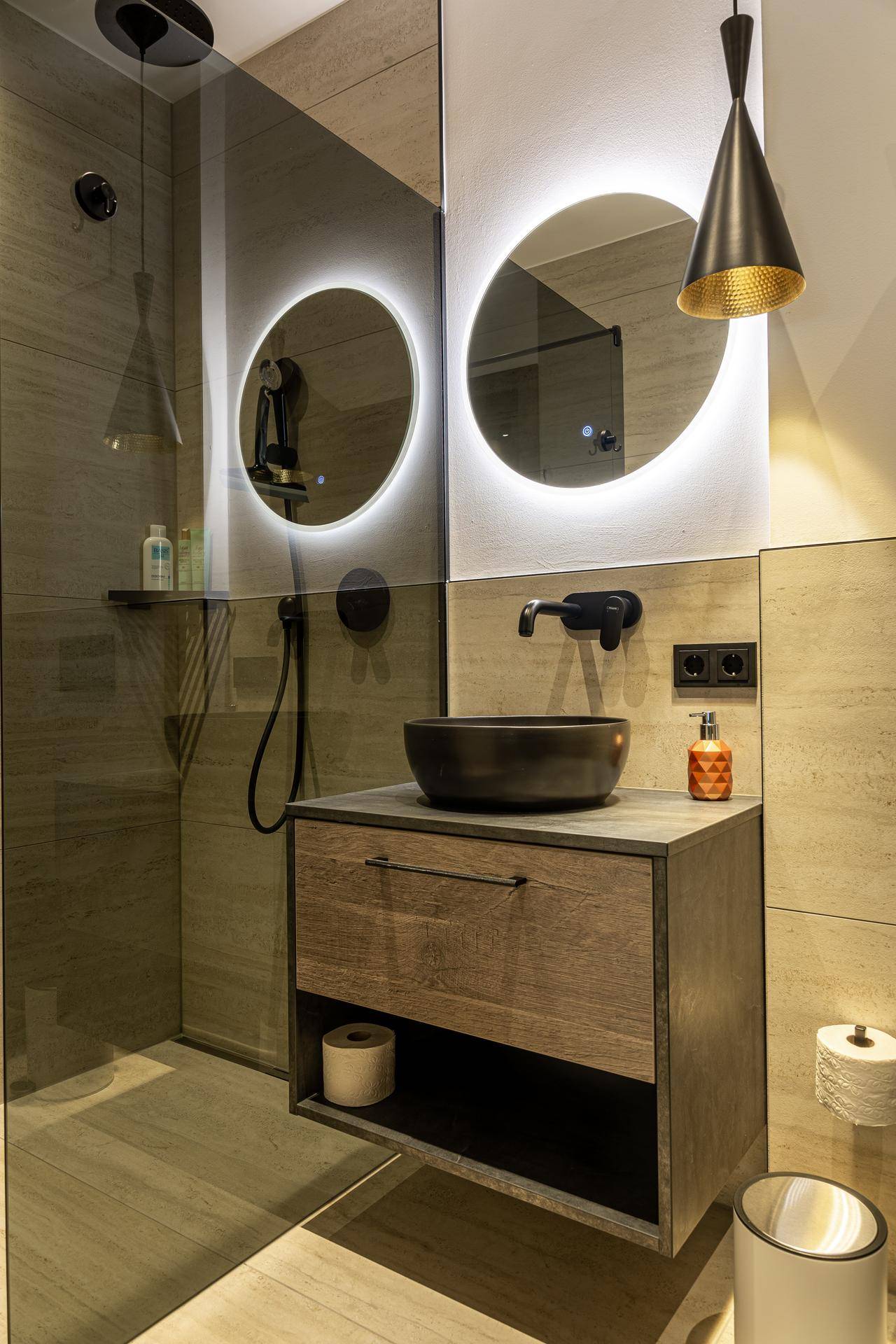 Modernes Badezimmer mit stilvollem Waschbecken, beleuchtetem Spiegel und begehbarer Dusche.