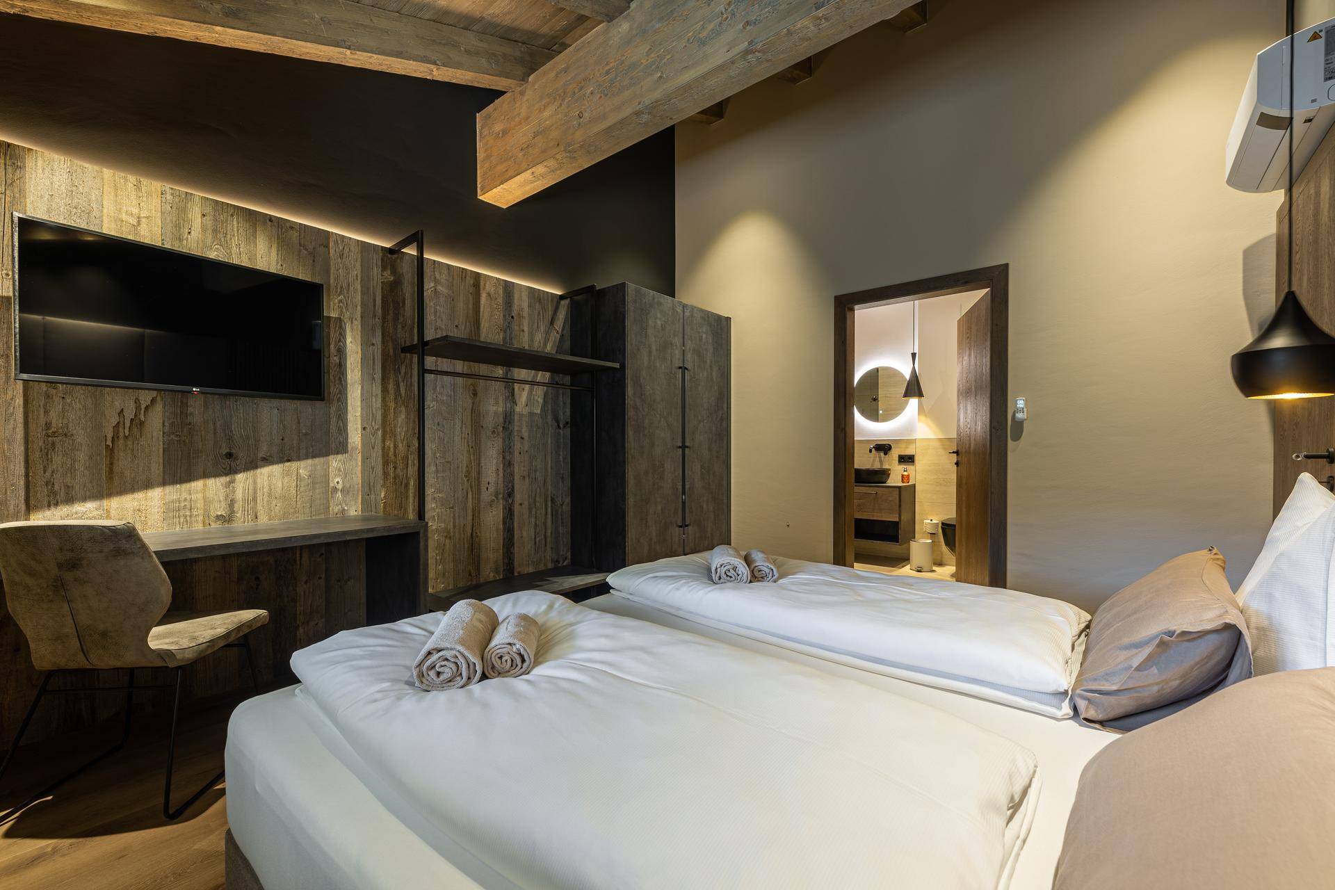 Komfortables Schlafzimmer mit Holzboden, modernem Bett und direktem Zugang zum Badezimmer.