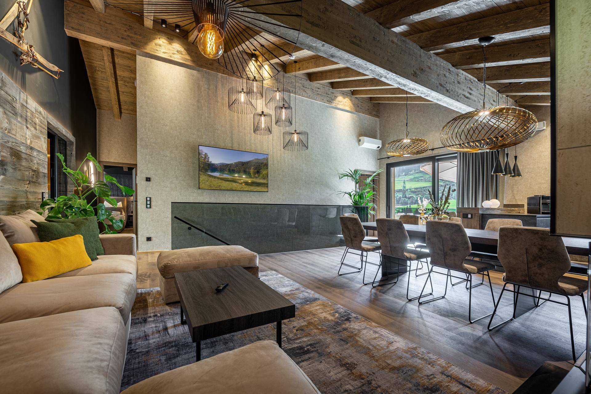 Komfortabler Wohn- und Essbereich mit großem Sofa, Holzbalkendecke und modernem Teppich.