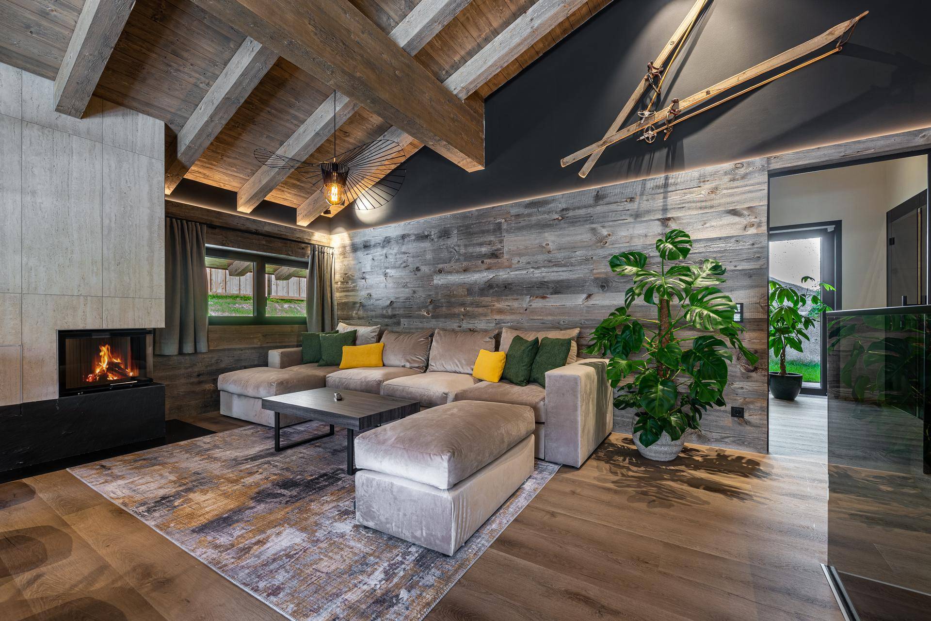 Gemütliches Wohnzimmer mit Kamin, großem Sofa und Holzbalkendecke für entspannte Abende.