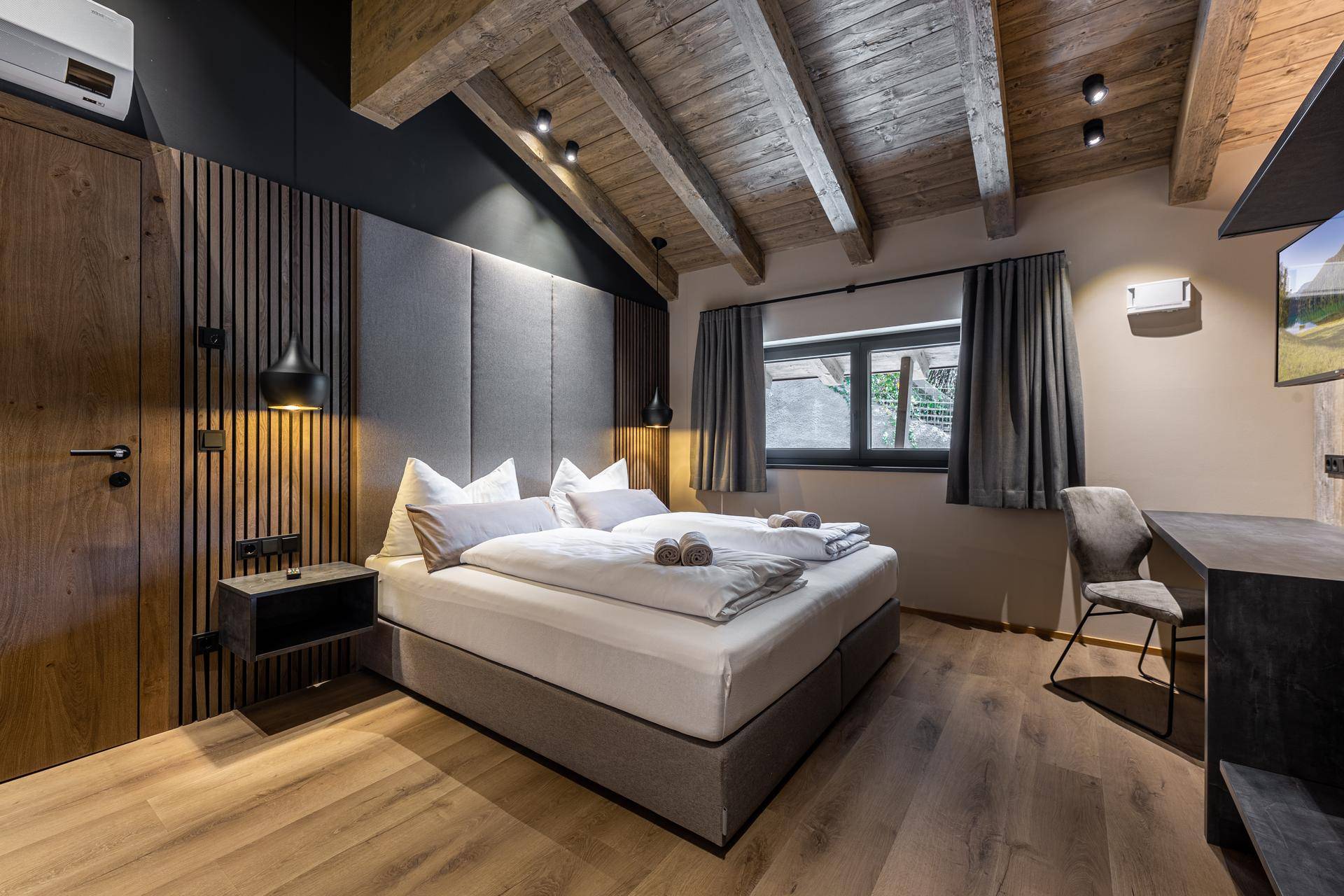 Gemütliches Schlafzimmer mit Holzbalkendecke, Holzboden und modernem Design.