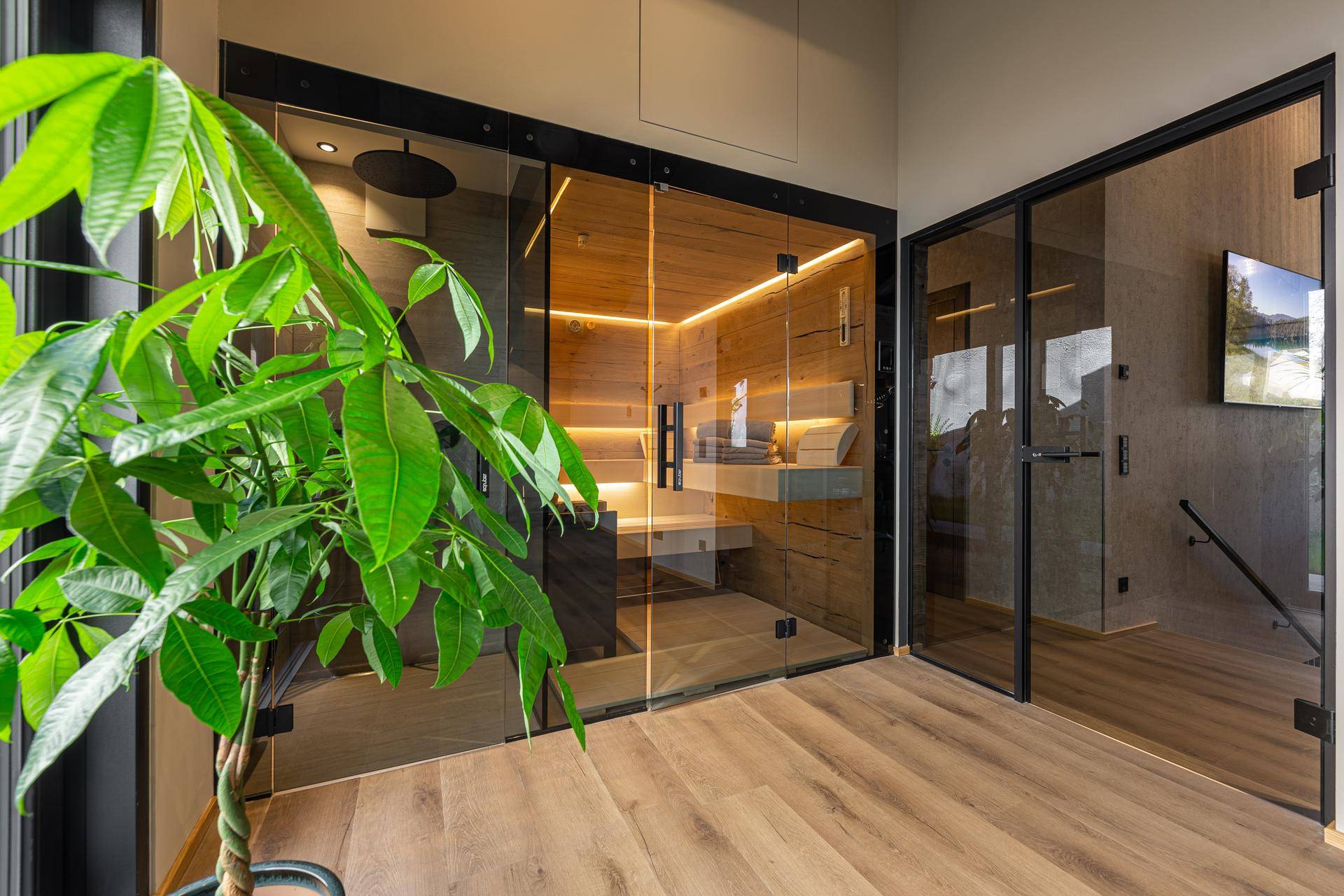 Heller Wellnessbereich mit Sauna, Glaswänden und Blick auf den Außenbereich.