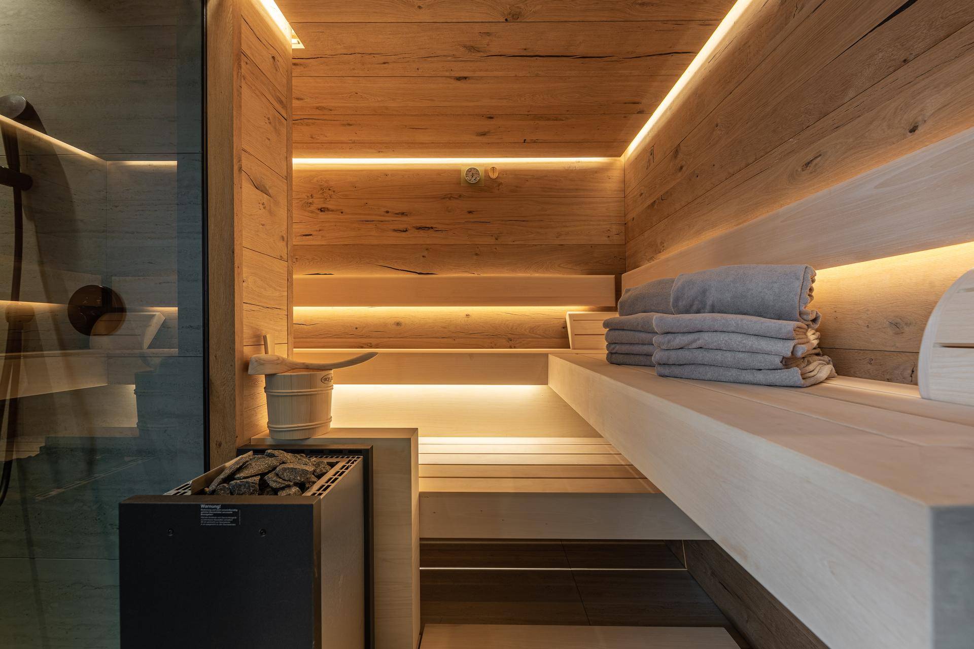 Moderne Sauna mit Holzverkleidung, indirekter Beleuchtung und bequemen Sitzbänken für Entspannung.