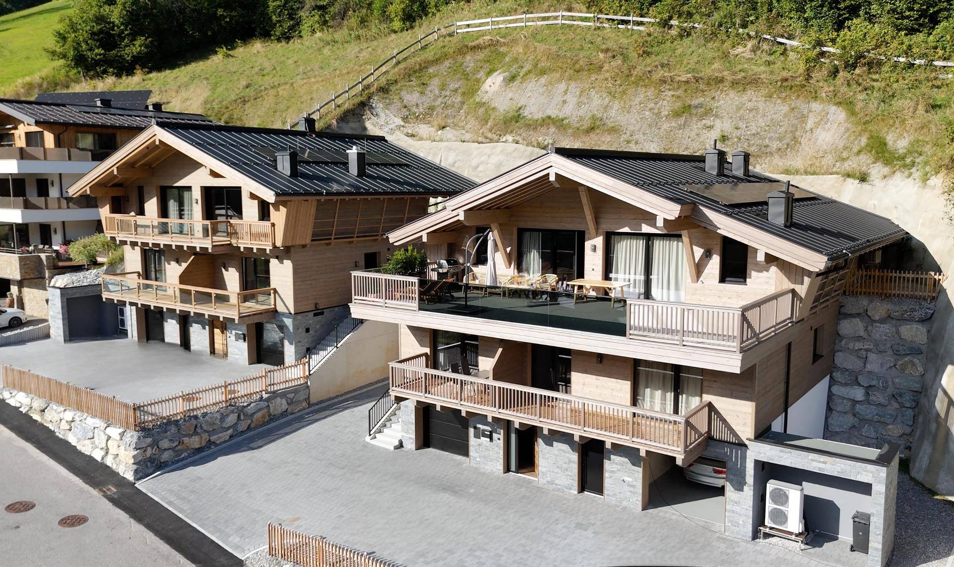 Moderne Chalet-Architektur mit Holzfassaden, Balkonen und Blick auf die umliegende Berglandschaft.