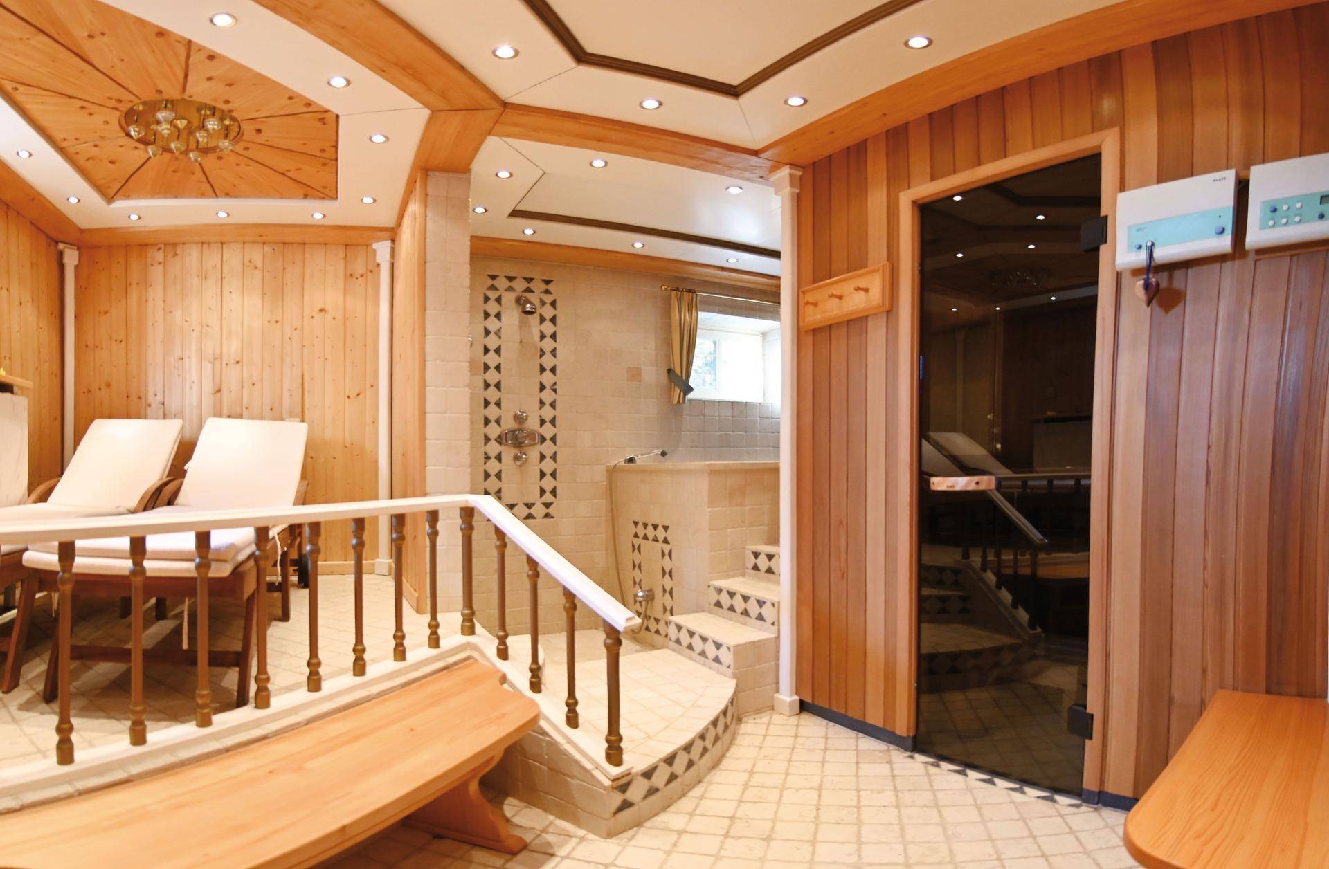 Gemütlicher Wellnessbereich mit Holzverkleidung, Sauna und Entspannungsliegen.