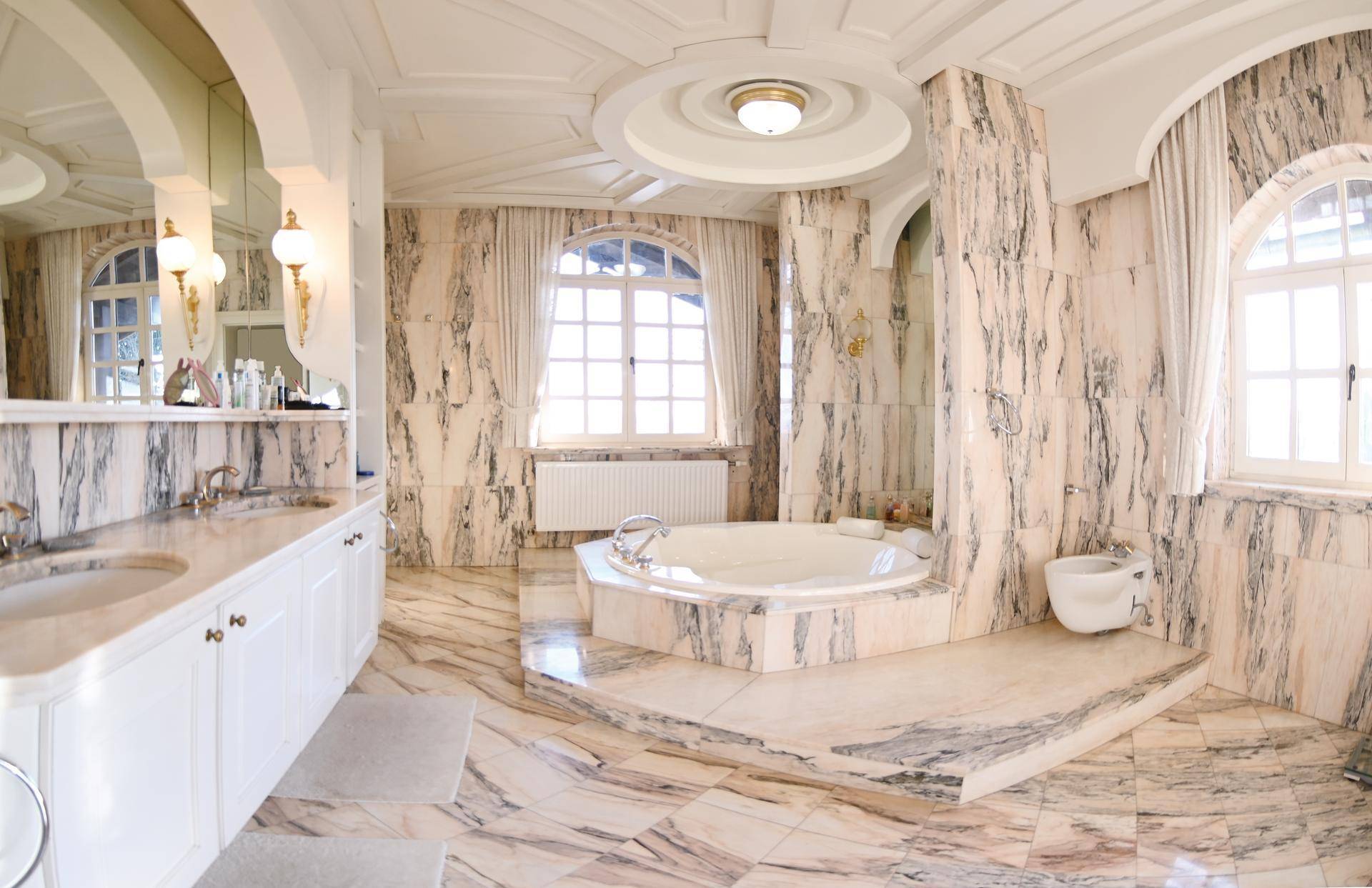 Luxuriöses Badezimmer mit Marmorverkleidung, Doppelwaschbecken, Eckbadewanne und Bidet.