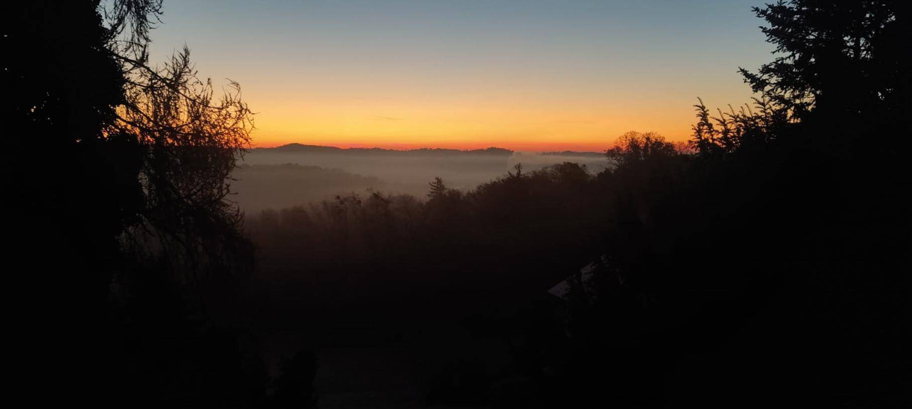 Malerischer Sonnenuntergang über einer nebligen Hügellandschaft mit weitem Blick.