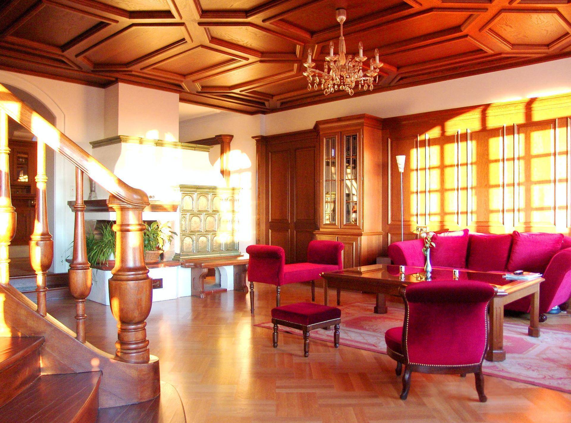 Geräumiges Wohnzimmer mit Holztäfelung, Kassettendecke, Parkettboden und traditionellem Kachelofen.