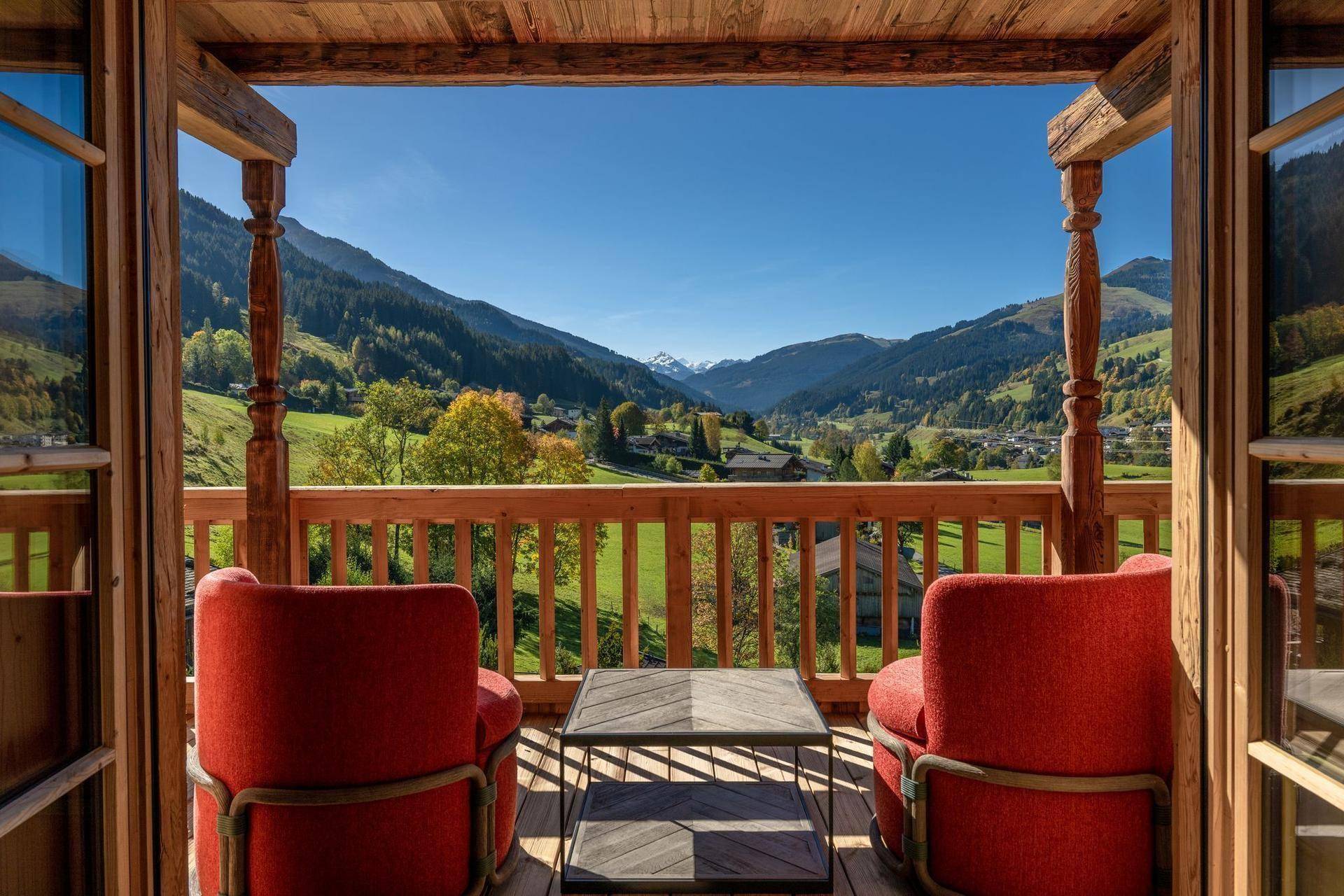 Holzbalkon mit bequemen Sitzgelegenheiten und atemberaubendem Blick auf die umliegende Berglandschaft.