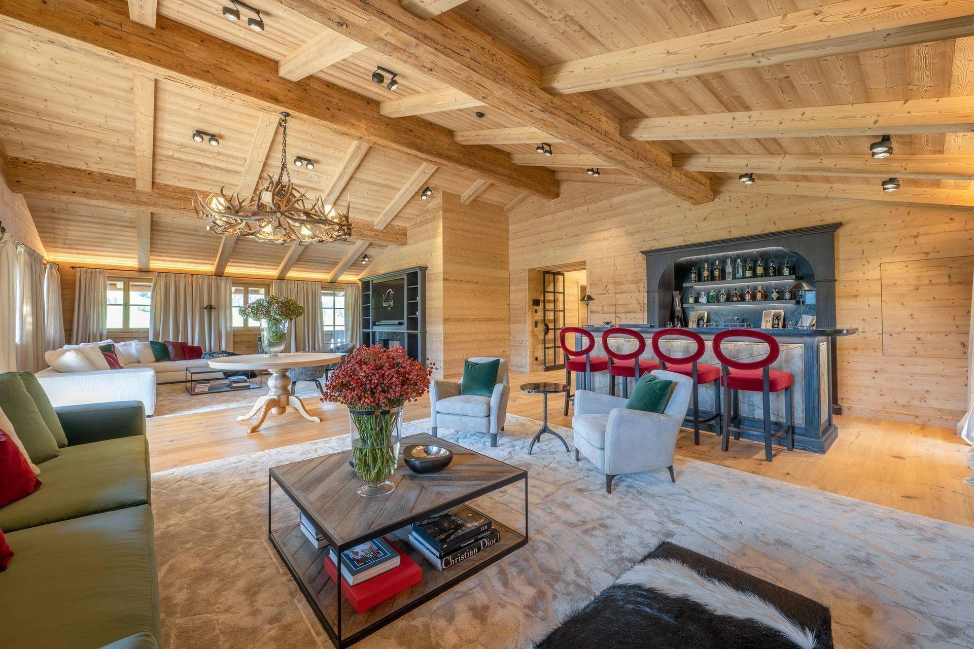 Geräumiges Wohnzimmer im alpinen Stil mit Holzwänden, sichtbaren Balken und einer eleganten Bar.