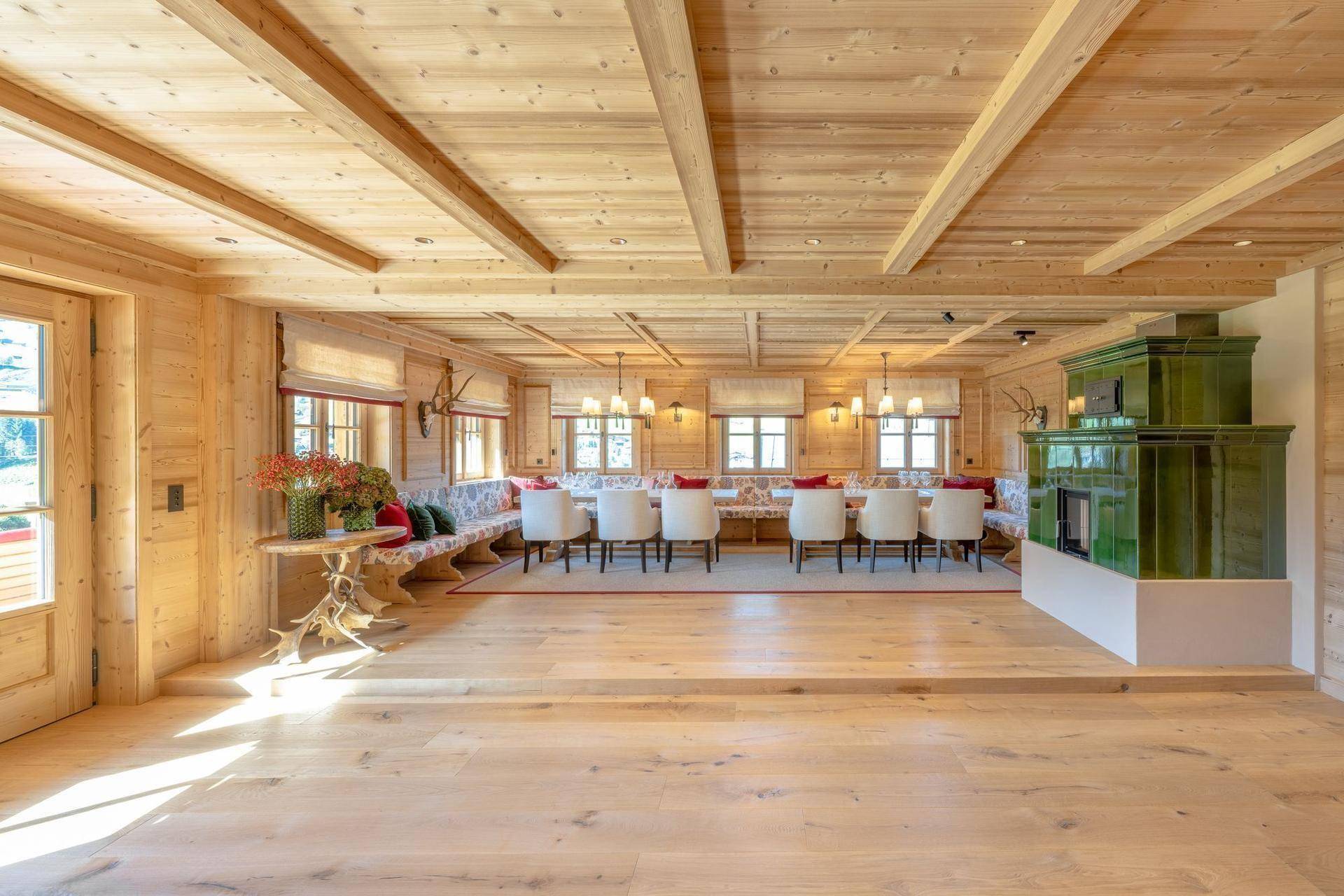 Großzügiger Essbereich mit Holzboden, traditionellem Kachelofen und langer Tafel für Gäste.