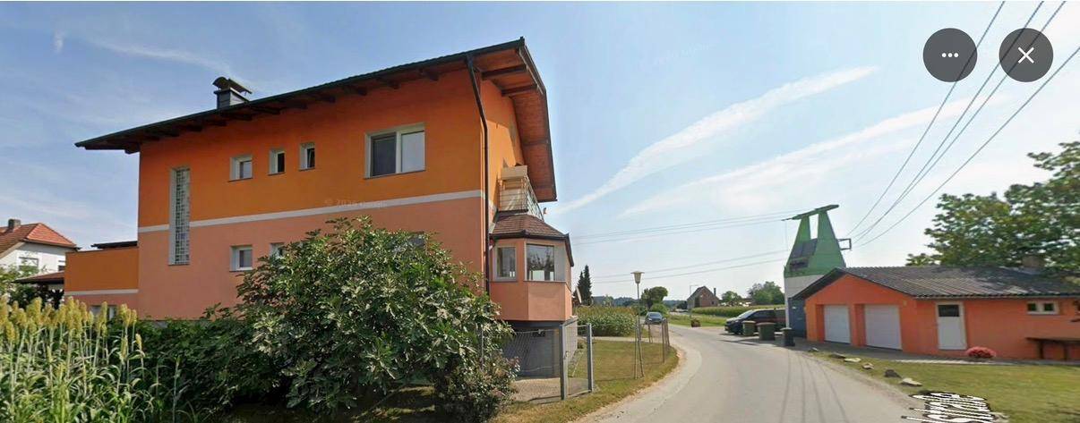 Seitenansicht des orangefarbenen Gebäudes mit ländlicher Umgebung und klarem Himmel.
