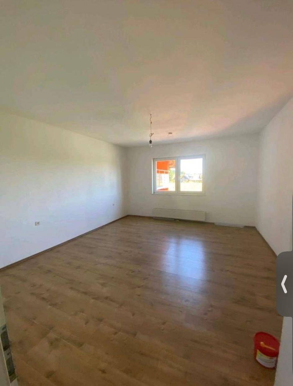 Lichtdurchflutetes Zimmer mit Laminatboden und Blick ins Grüne durch das Fenster.