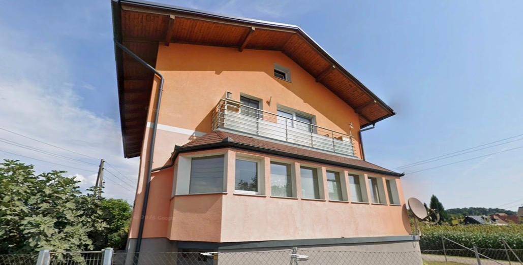 Detailansicht der Gebäudefassade mit Balkon und verglastem Erker im Erdgeschoss.