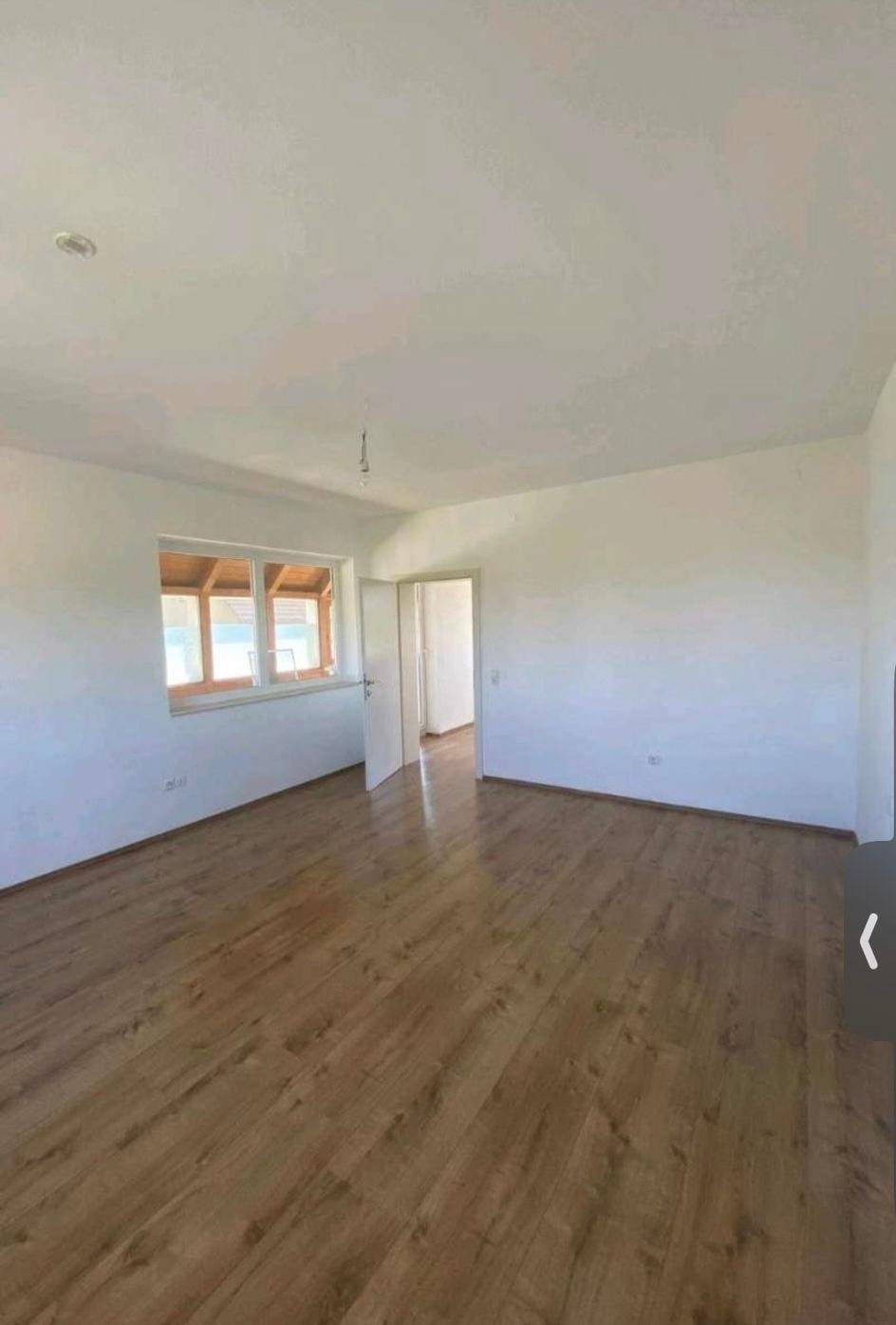 Geräumiges Zimmer mit Laminatboden und Zugang zu einem hellen Wintergarten oder einer Loggia.