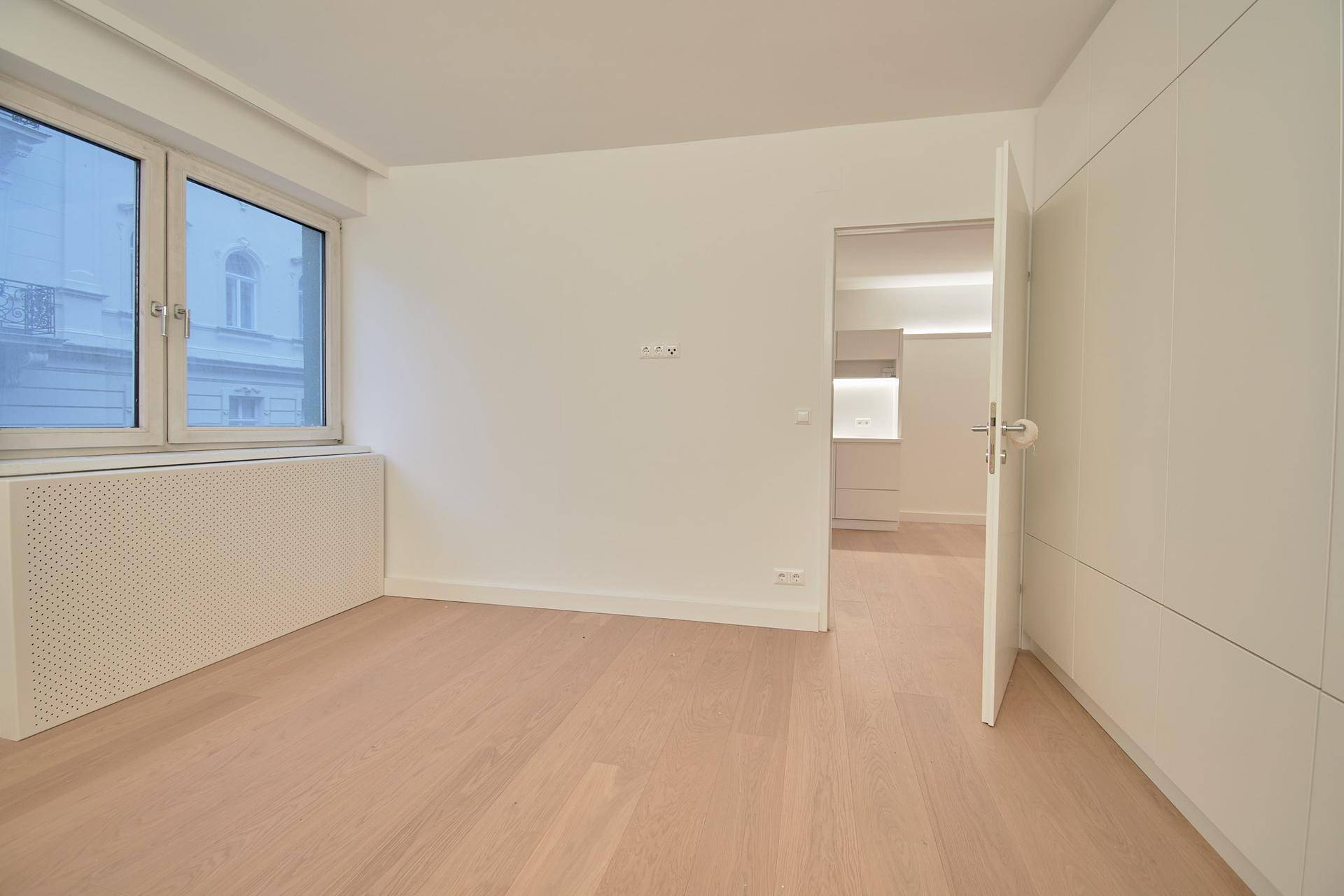 Heller Raum mit großem Fenster und praktischen Einbauschränken, ideal als Schlafzimmer.