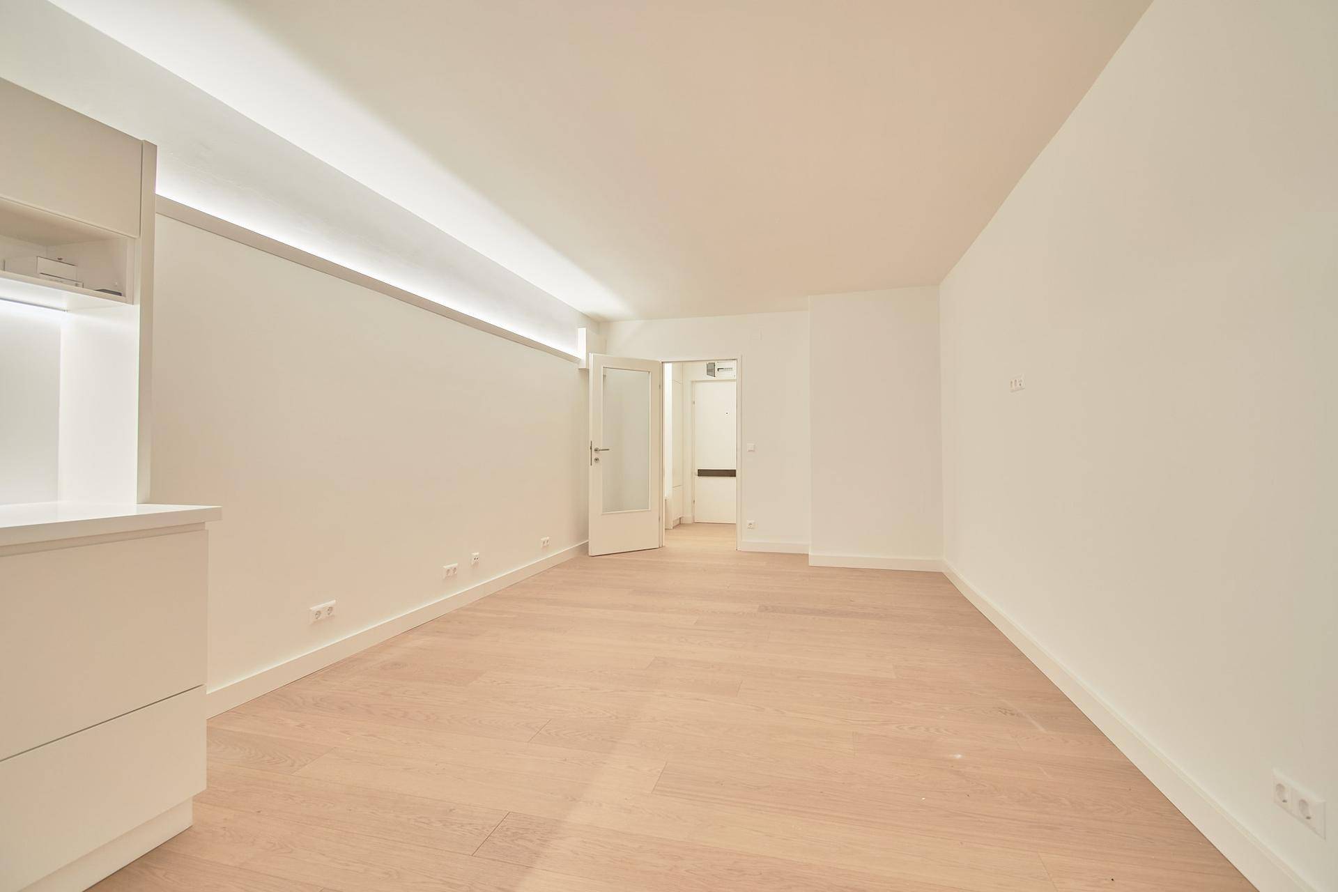 Geräumiger, heller Raum mit Holzboden und weiß gestrichenen Wänden, bereit zum Einrichten.