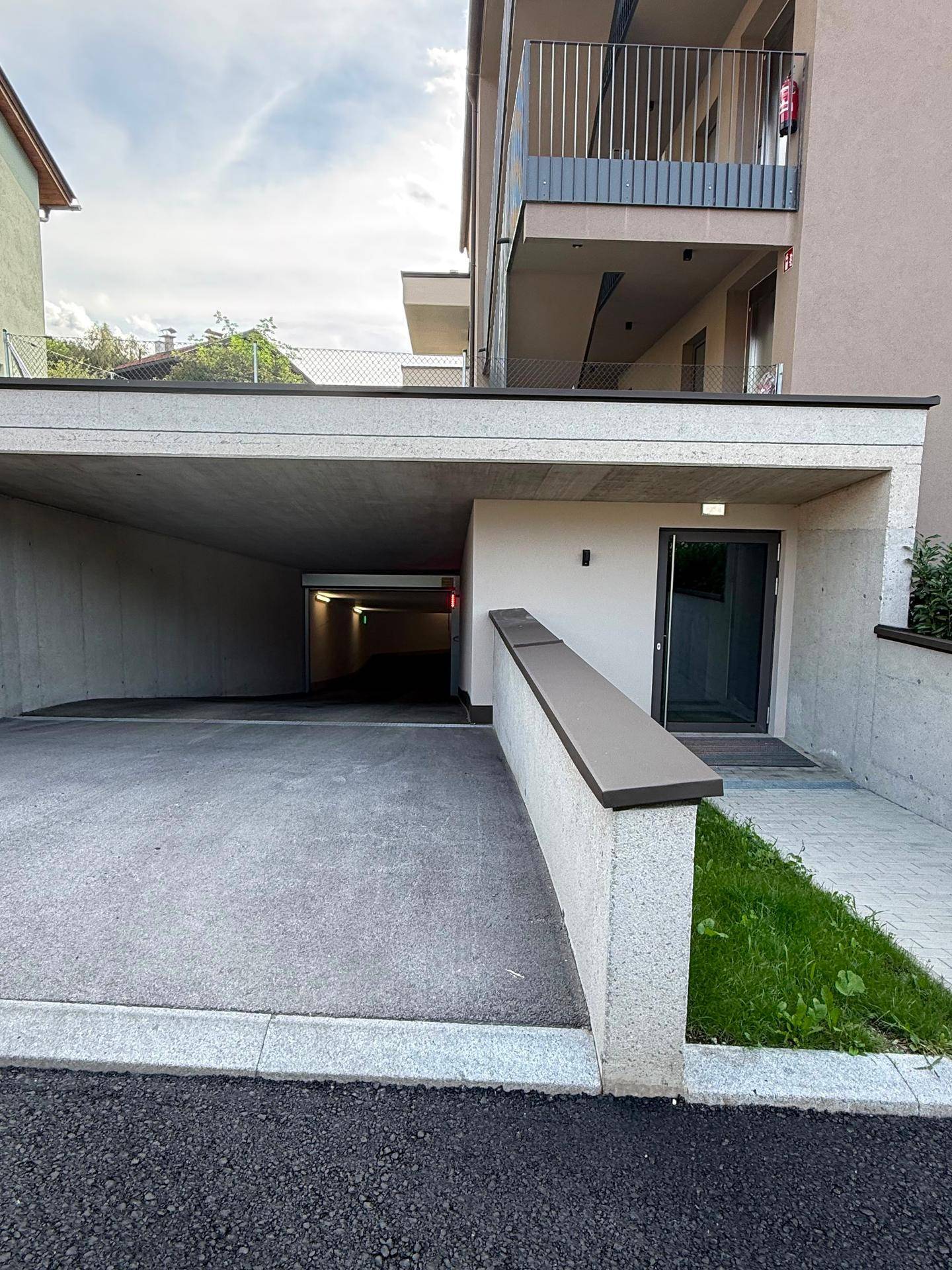 Eingang zu einer Tiefgarage mit Rampe und direktem Zugang zum modernen Wohngebäude.