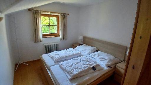 Schlafzimmer mit zwei Einzelbetten, Holzboden und Fenster mit Blick ins Grüne.