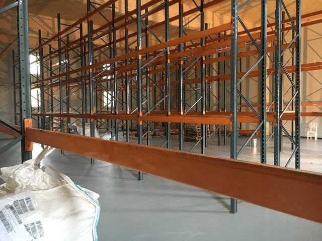 Leere Lagerhalle mit hohen Regalsystemen und einem robusten Betonboden, bereit zur Nutzung.
