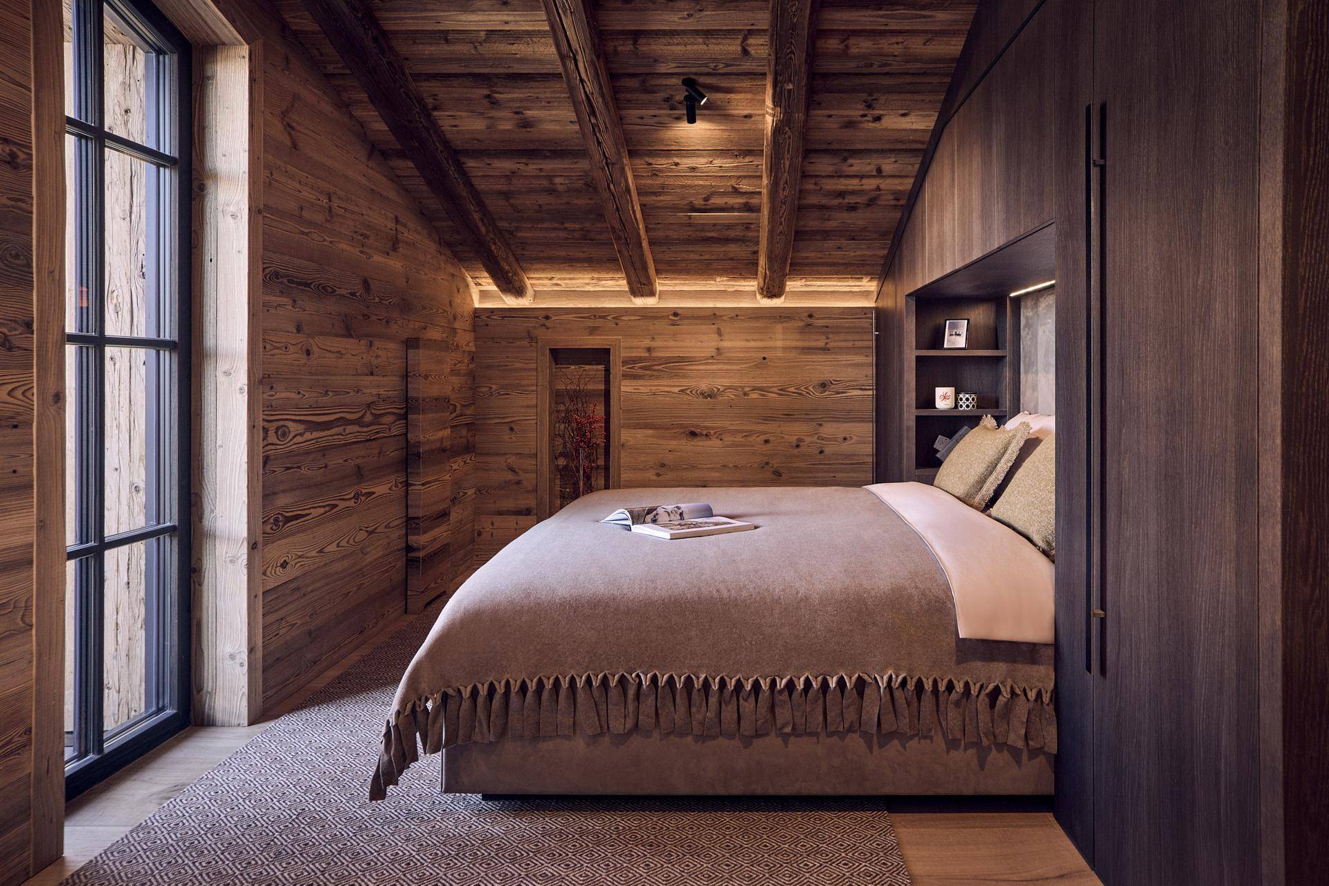 Ruhiges Schlafzimmer mit Holzwänden, integriertem Kopfteil und indirekter Beleuchtung.