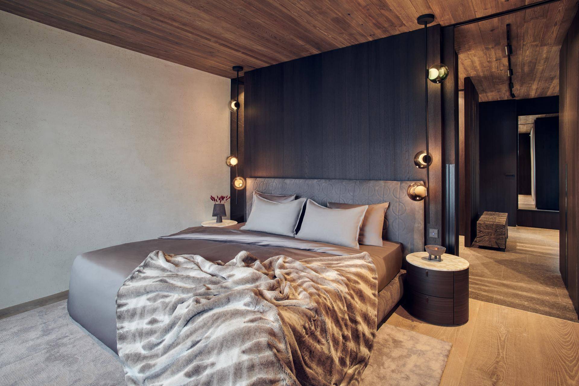 Modernes Schlafzimmer mit Holzboden, dunkler Akzentwand und stilvoller Beleuchtung.