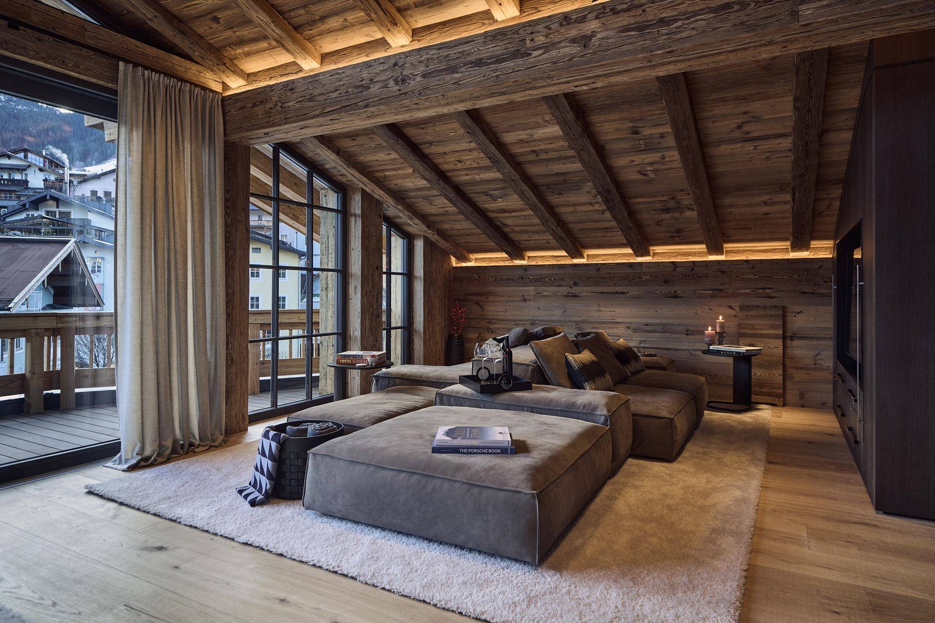 Großzügiger Wohnbereich mit Holzbalkendecke, bequemen Sofas und Zugang zu einem Balkon.