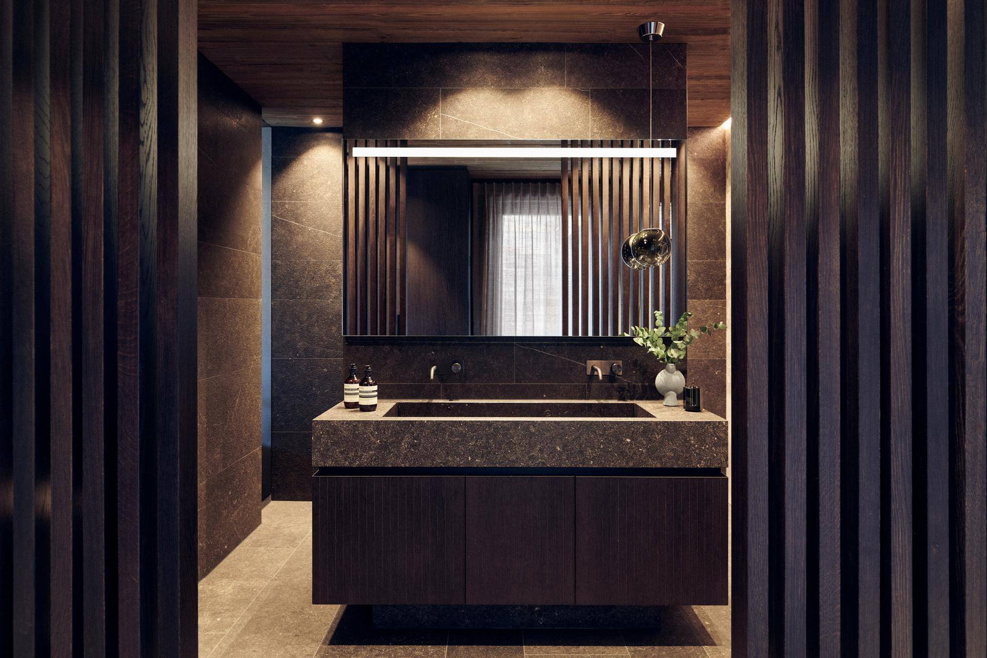 Elegantes Badezimmer mit Doppelwaschbecken, dunklen Fliesen und Holzvertäfelung.