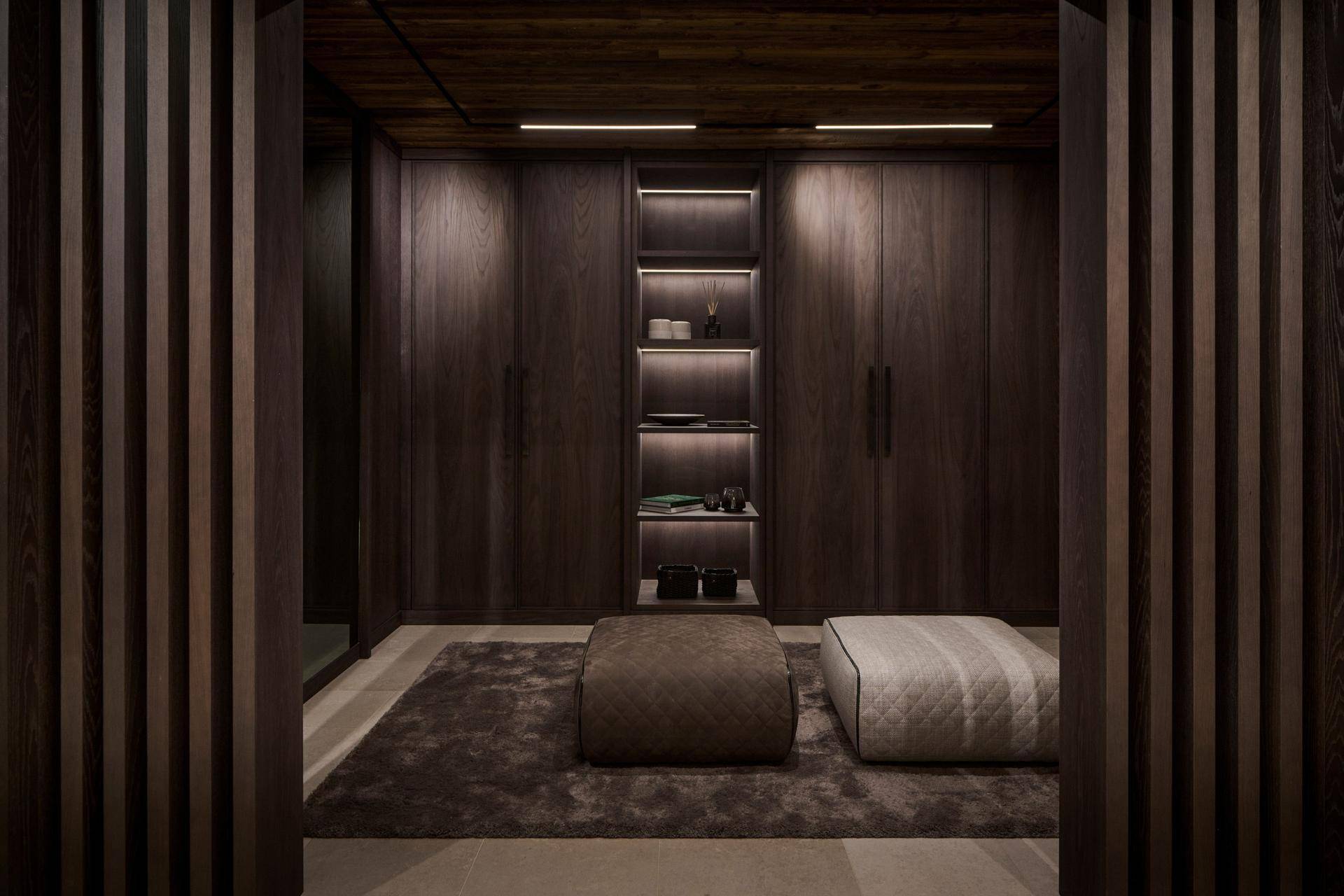 Geräumiger begehbarer Kleiderschrank mit eleganten Einbauschränken und Sitzgelegenheiten.