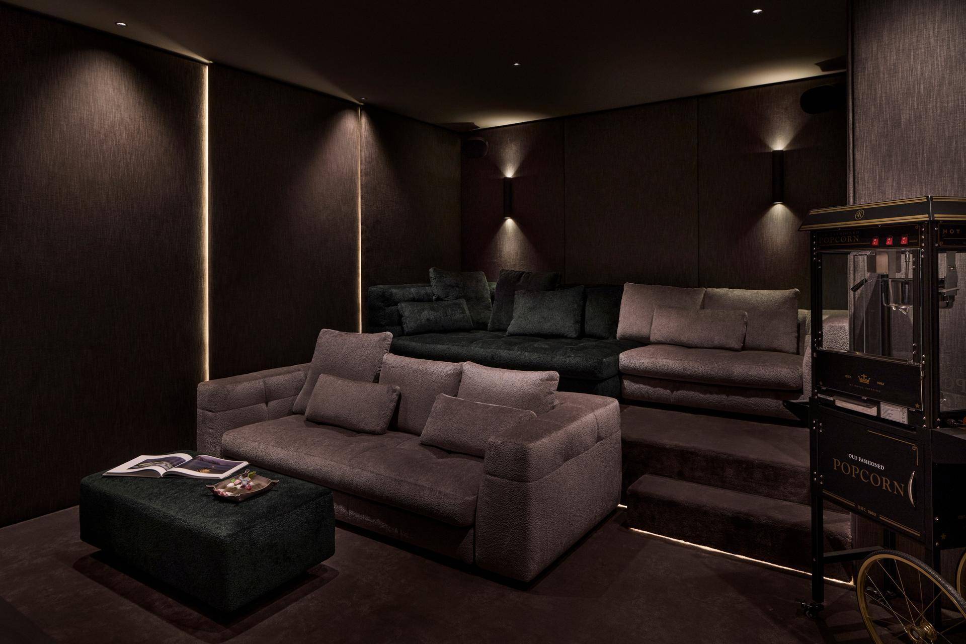 Exklusiver Medienraum mit gestuften Sitzgelegenheiten und Popcornmaschine für das ultimative Kinoerlebnis.