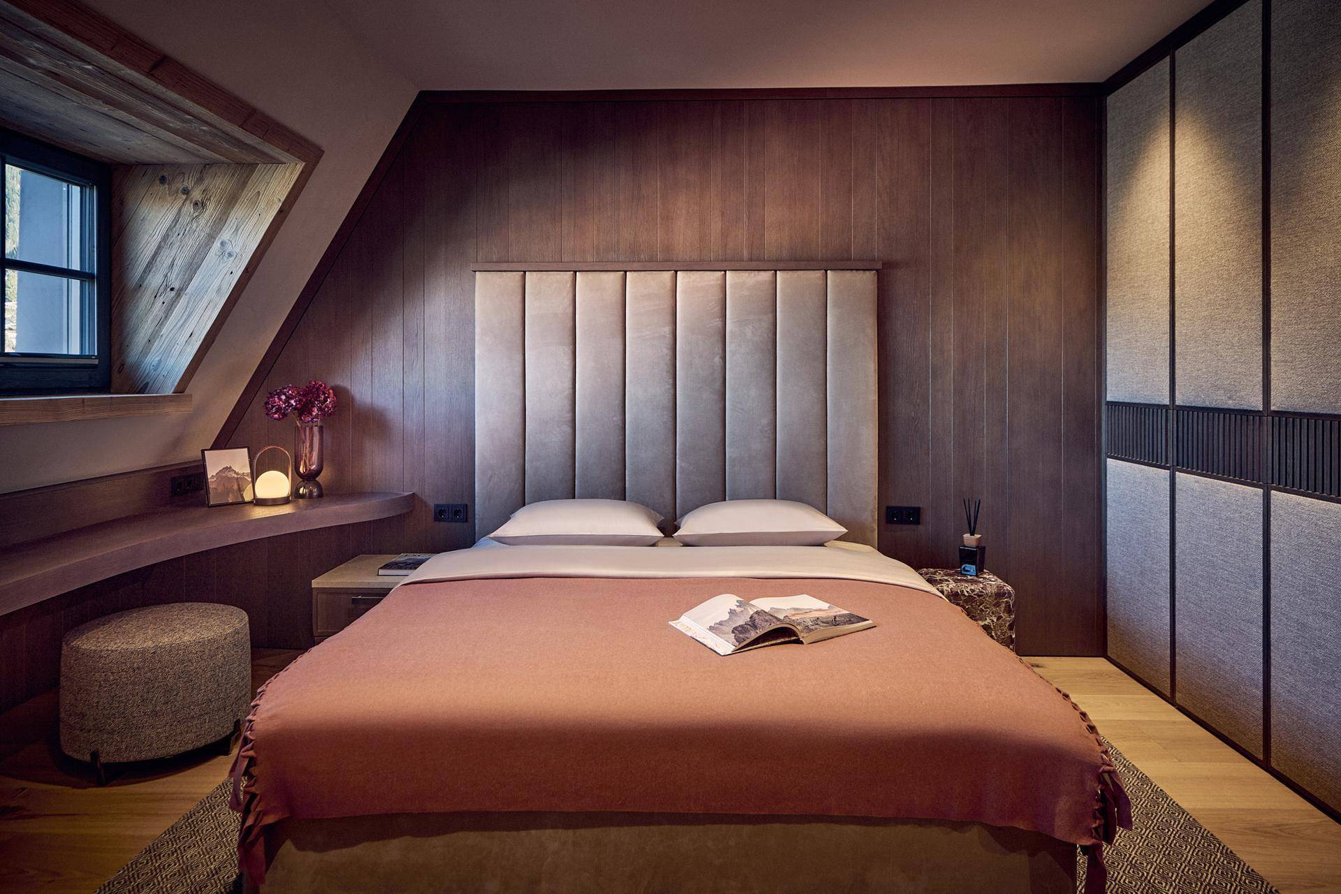 Gemütliches Schlafzimmer im Dachgeschoss mit Holzwänden, schrägen Decken und integrierten Möbeln.