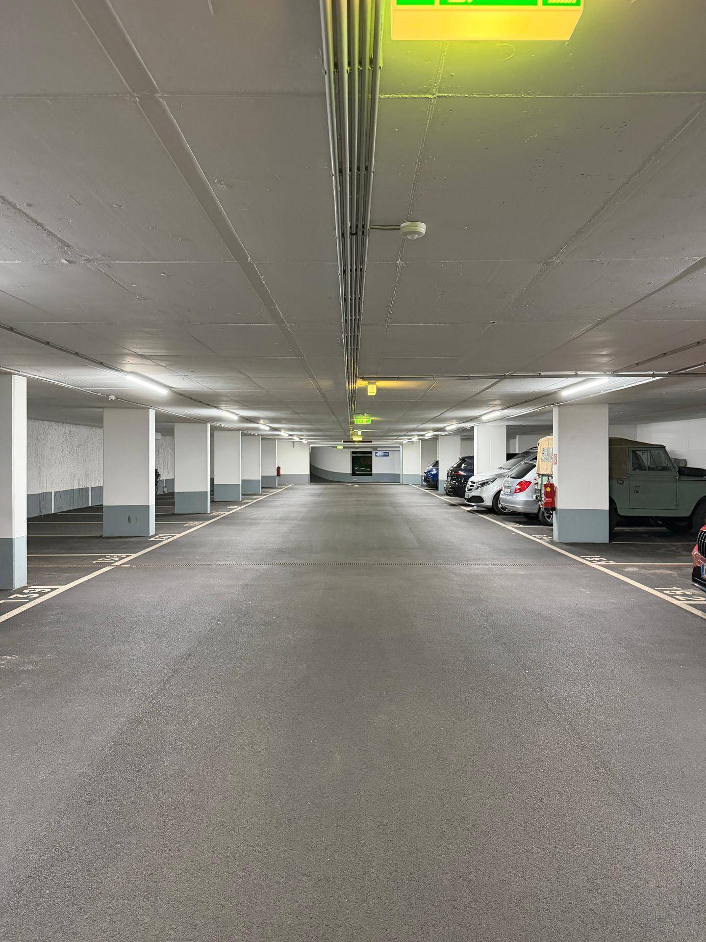 Lange und helle Tiefgaragenzufahrt mit zahlreichen Stellplätzen und guter Beleuchtung.