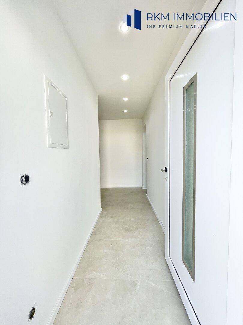 Moderner Eingangsbereich mit Fliesenboden und Einbaustrahlern an der Decke.