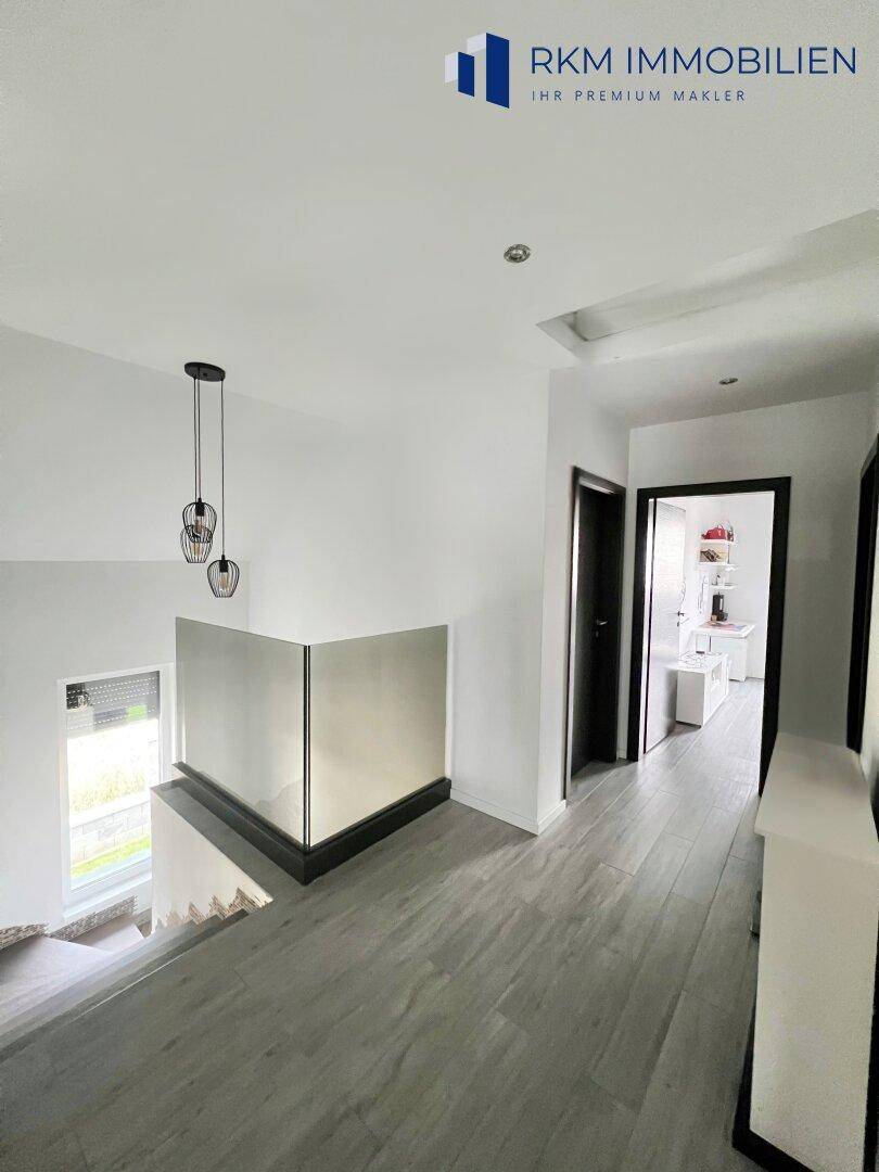 Heller Flur im Obergeschoss mit Glasgeländer und Blick auf die untere Etage.