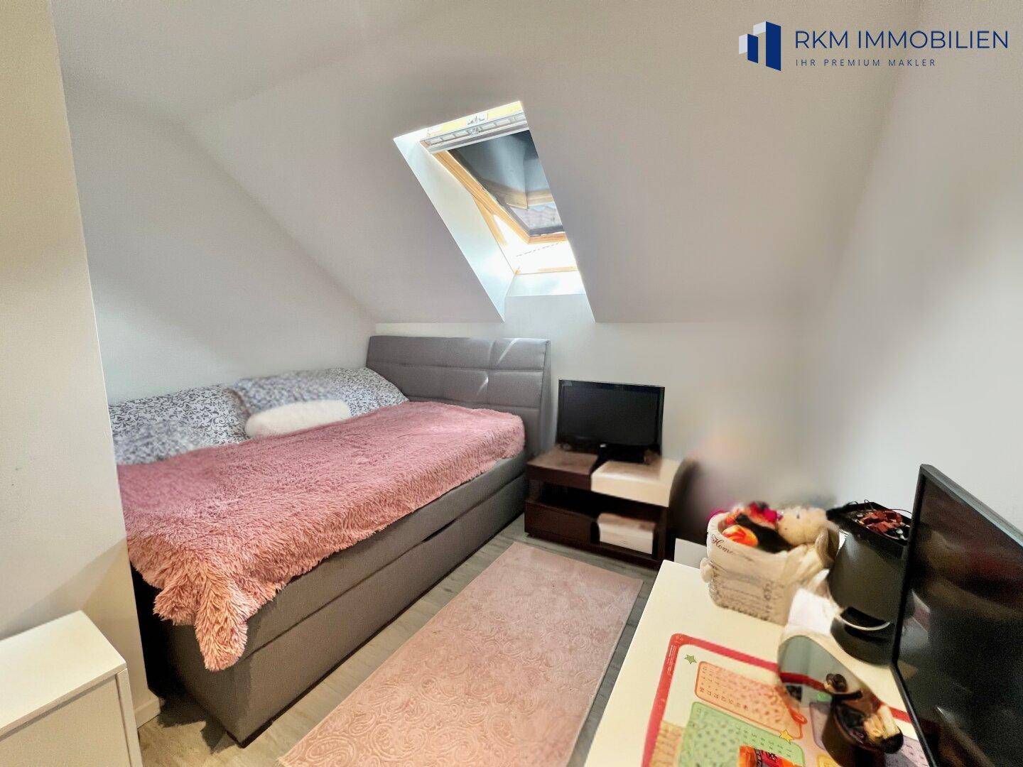 Gemütliches Schlafzimmer im Dachgeschoss mit Dachfenster, Einzelbett und Teppichläufer.