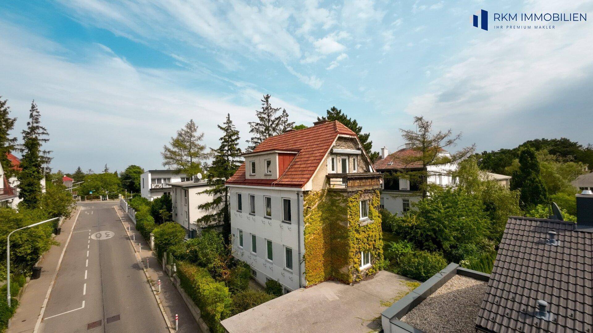 Luftaufnahme des Wohnhauses mit umliegender Nachbarschaft, Straße und viel Grün.