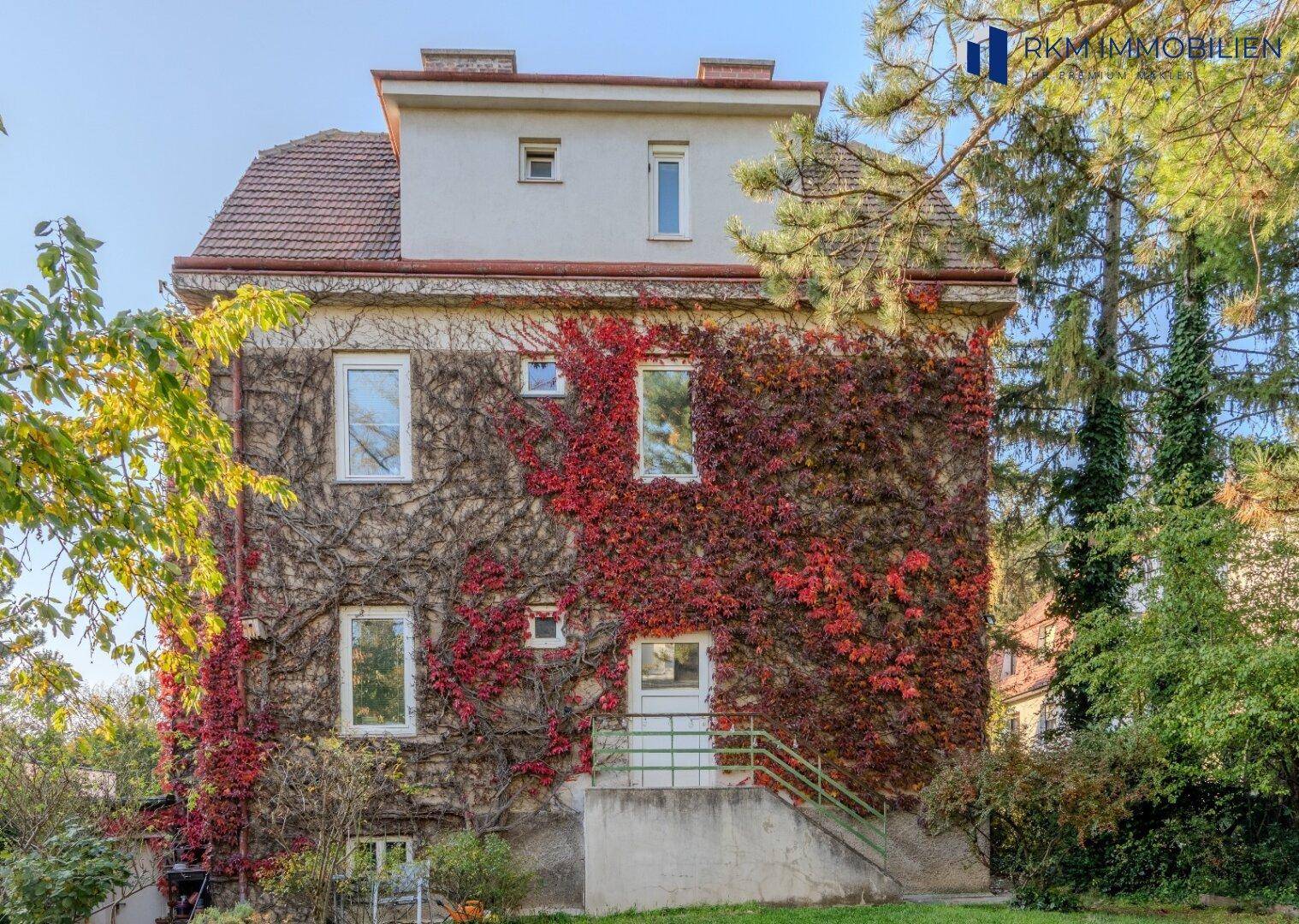 Rückansicht des Hauses mit stark bewachsener Fassade und Außentreppe.