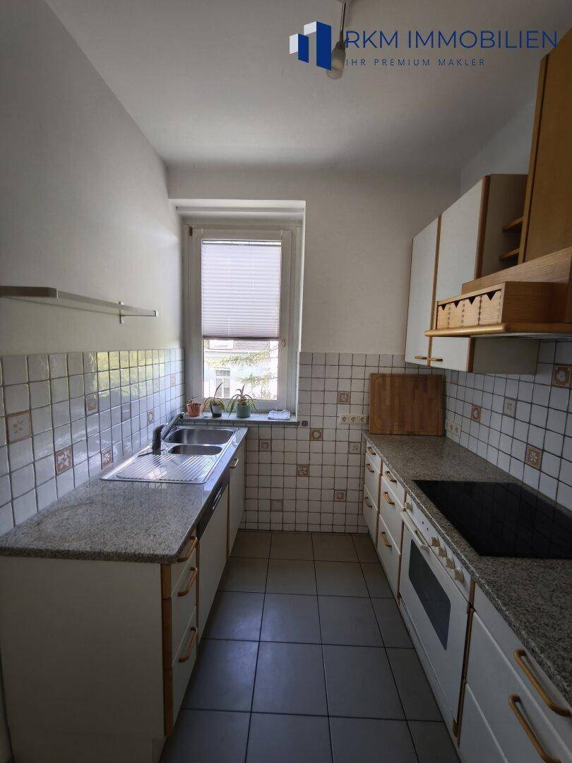 Funktionale Küche mit älteren Einbauschränken, Granitarbeitsplatte und Fliesenboden.