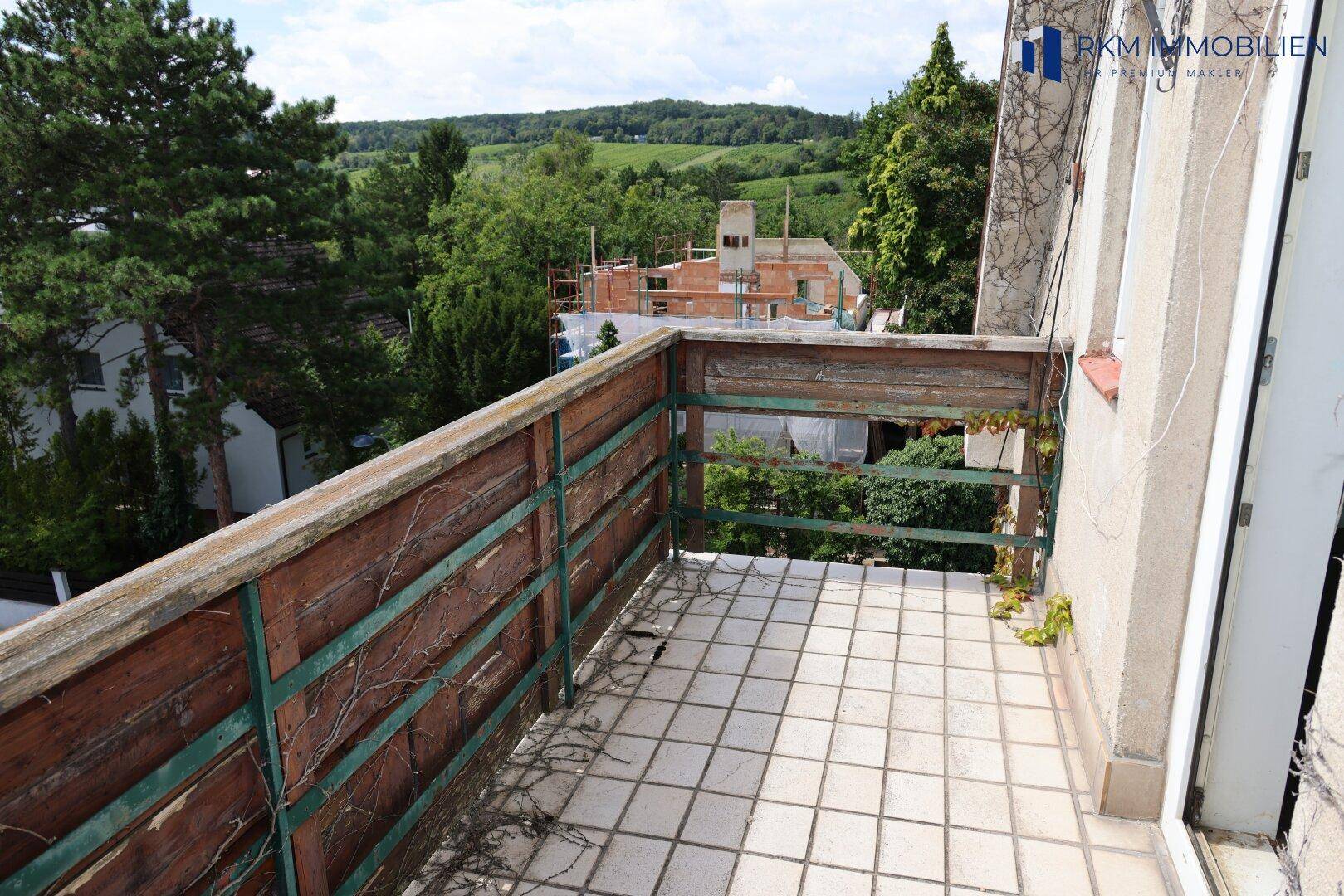 Balkon mit Fliesenboden und Holzbalkonbrüstung, bietet einen weiten Blick ins Grüne.