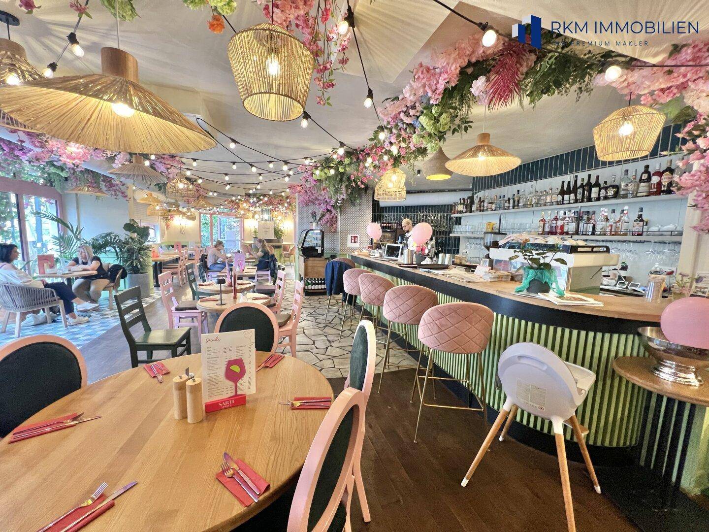 Lebhafter Restaurantbereich mit Bar, verschiedenen Sitzgelegenheiten und üppiger Blumendekoration.